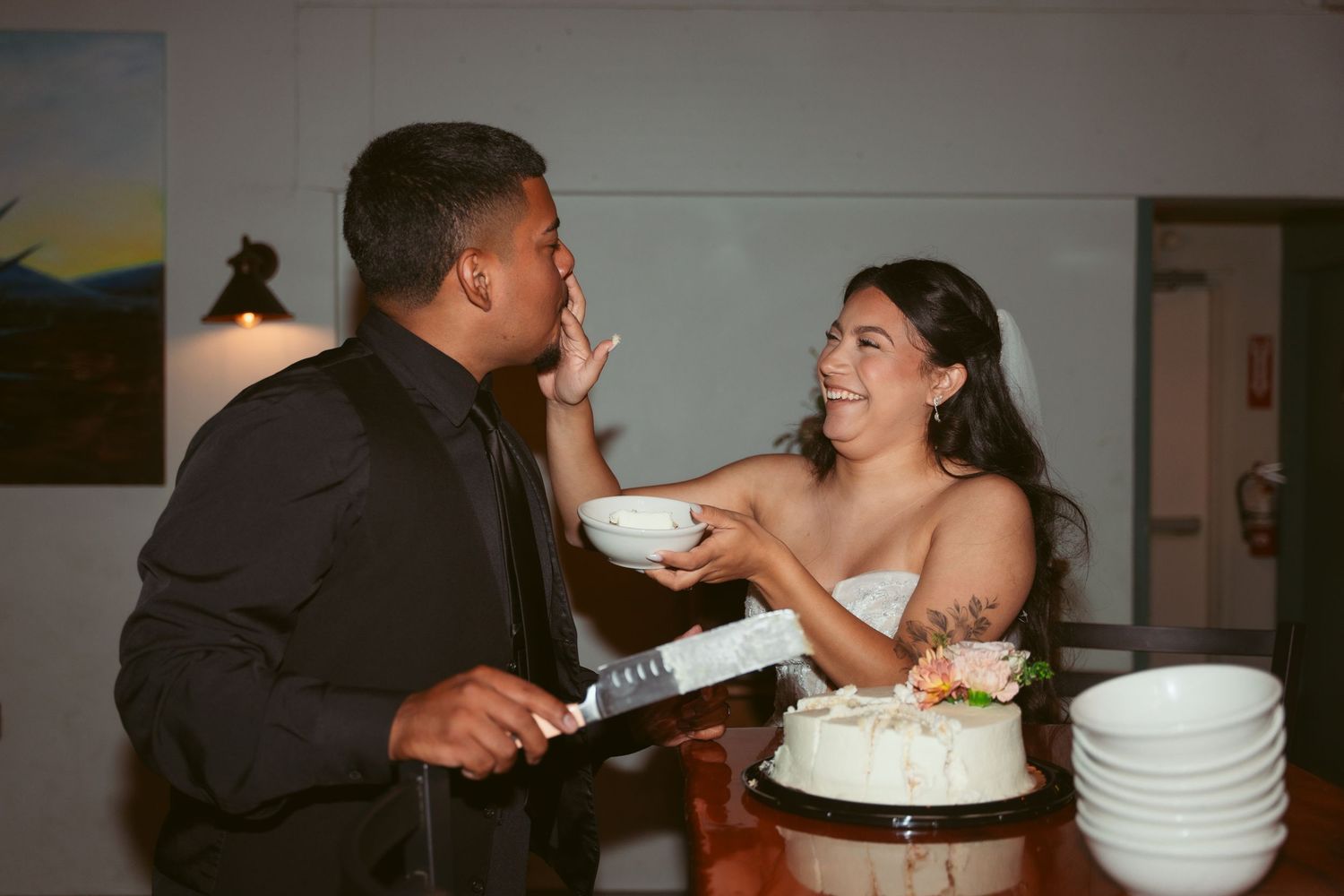 Newlyweds playfully feeding each other cake during their wedding reception.