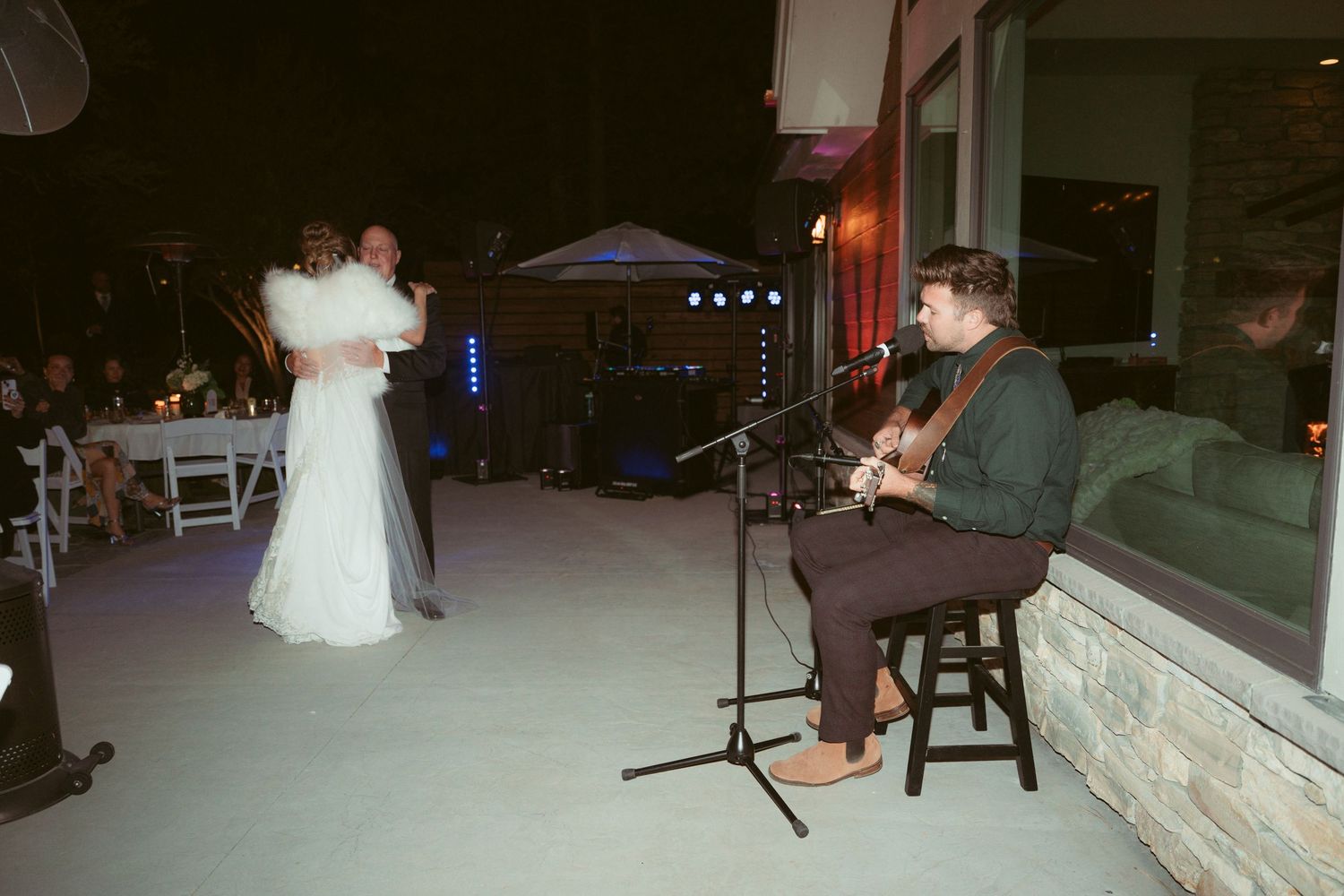 Newlyweds dancing together at their reception with blue accent lighting in the background.