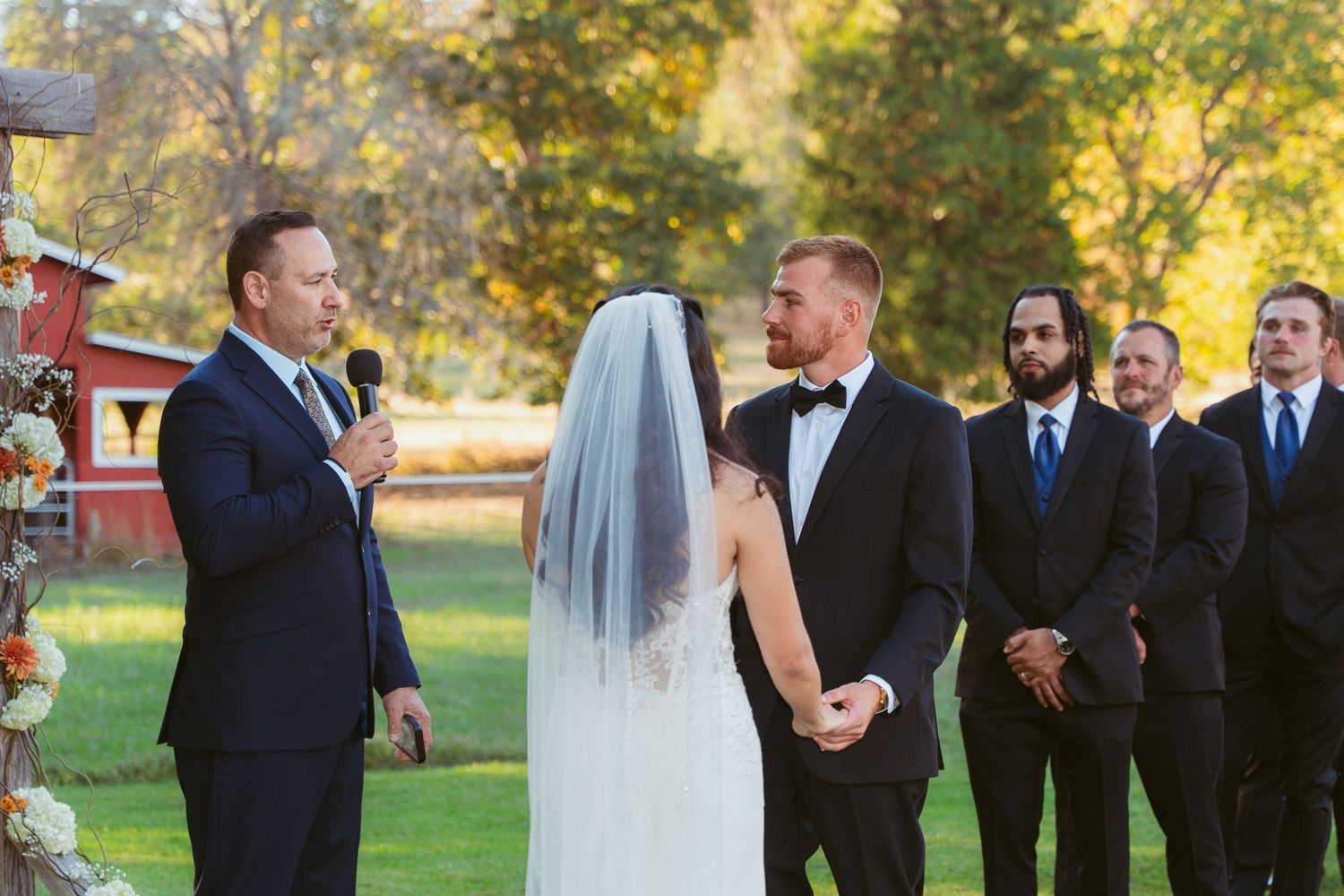 Wedding party poses together during outdoor autumn ceremony.