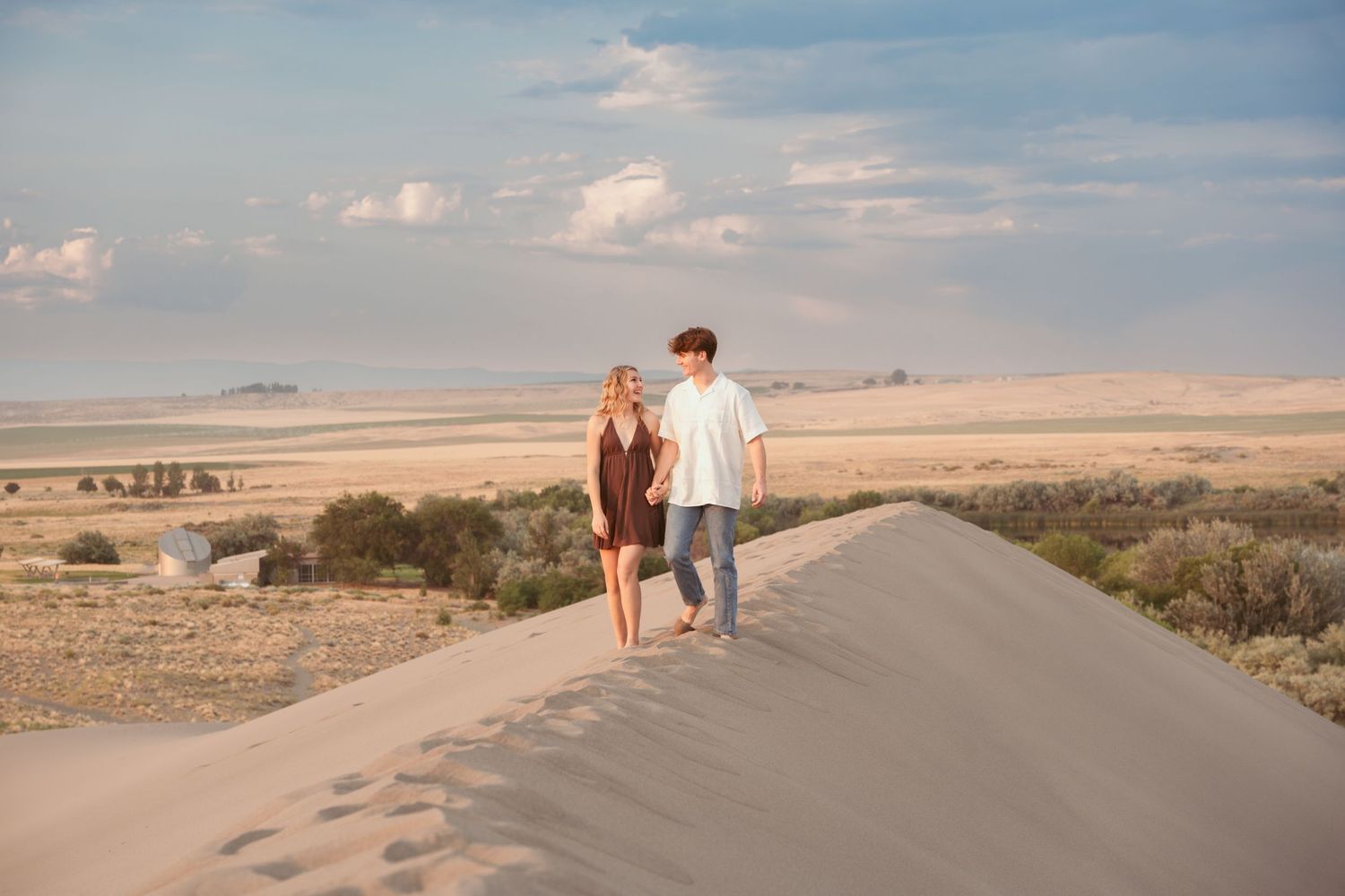 Desert landscape with couple walking along winding road during sunset.