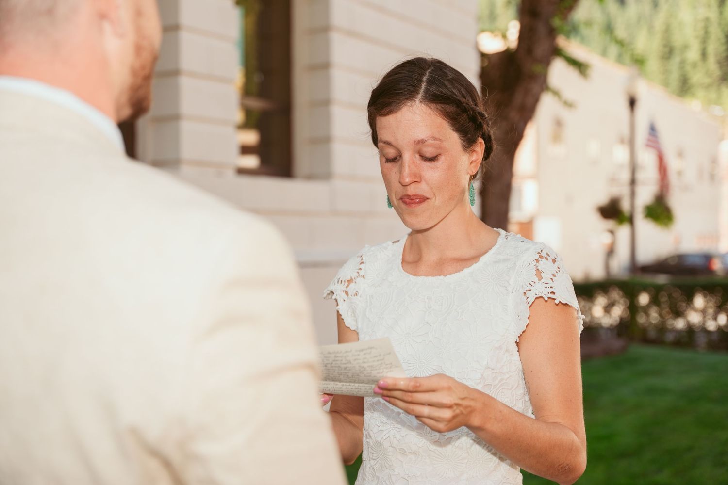 A couple reads personal letters to each other during an outdoor wedding ceremony.