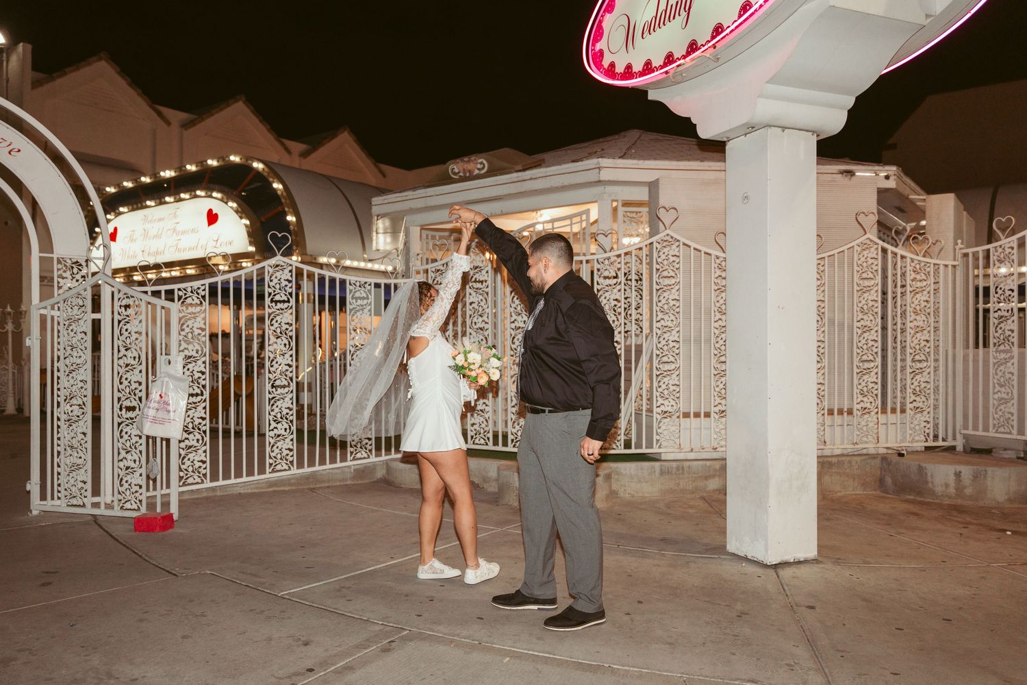 Couple sharing a romantic moment under illuminated columns at night.