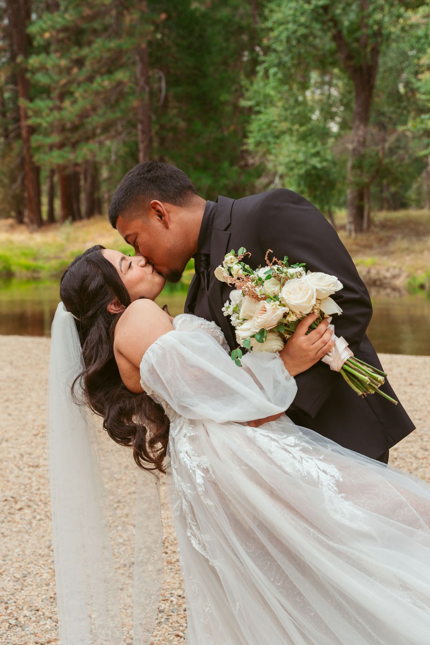 Newlyweds share a passionate kiss during their wedding photoshoot in Yosemite Valley.