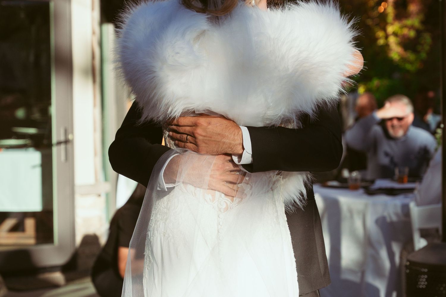 An intimate embrace captured during a wedding dance on an outdoor patio.