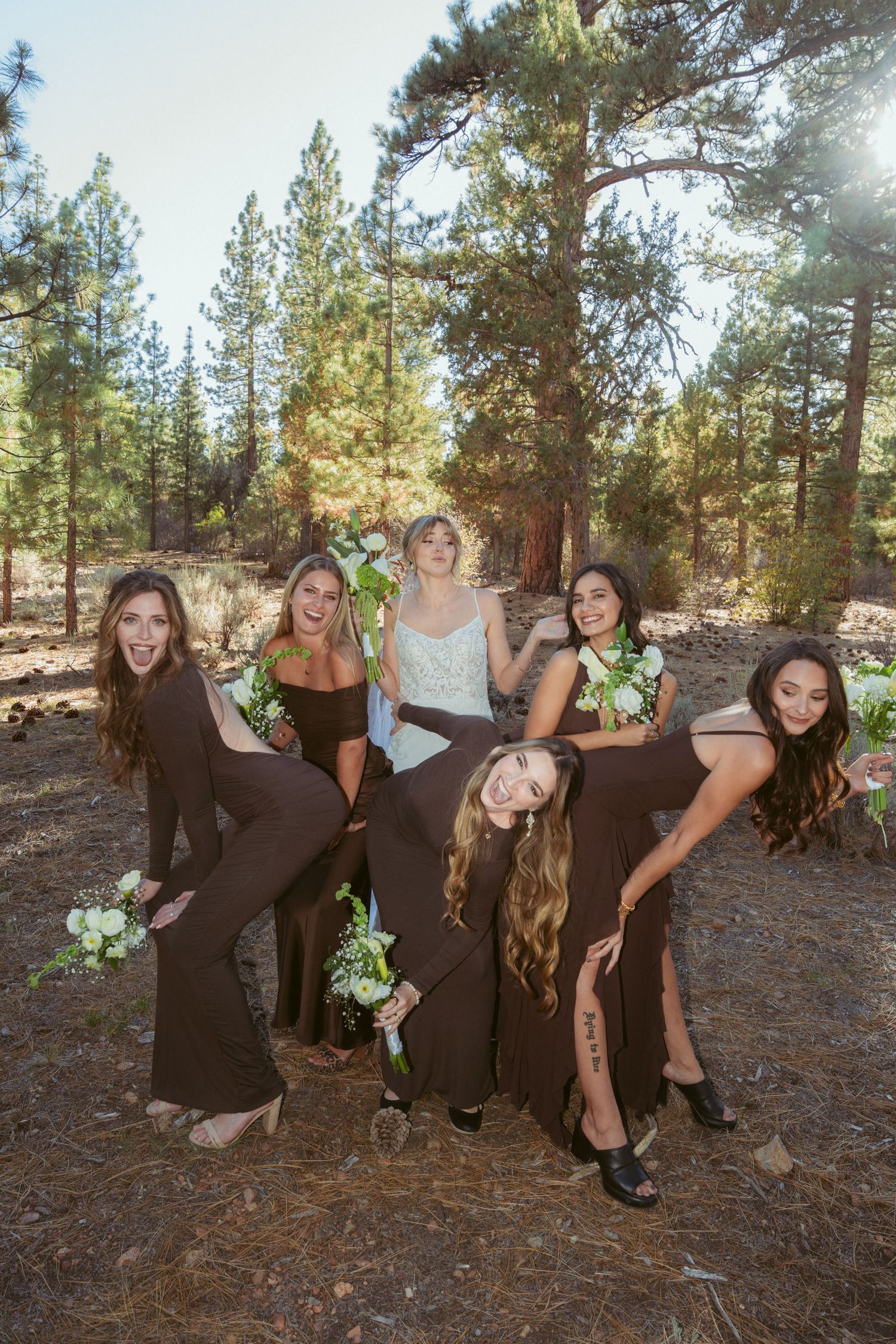 Fun candid shots of bridal party posing playfully in forest environment.