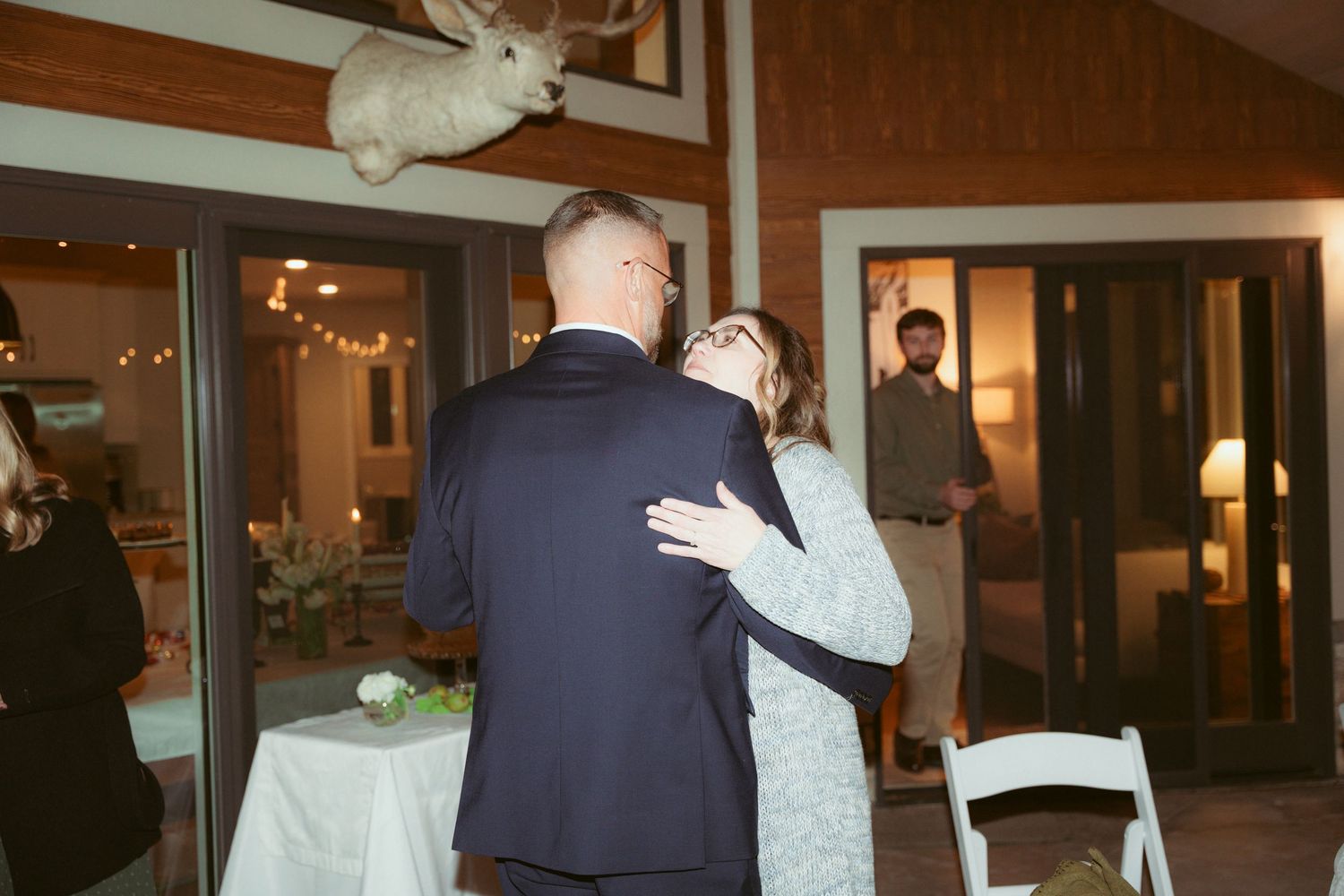 A couple sharing a dance moment at their wedding reception with string lights overhead.