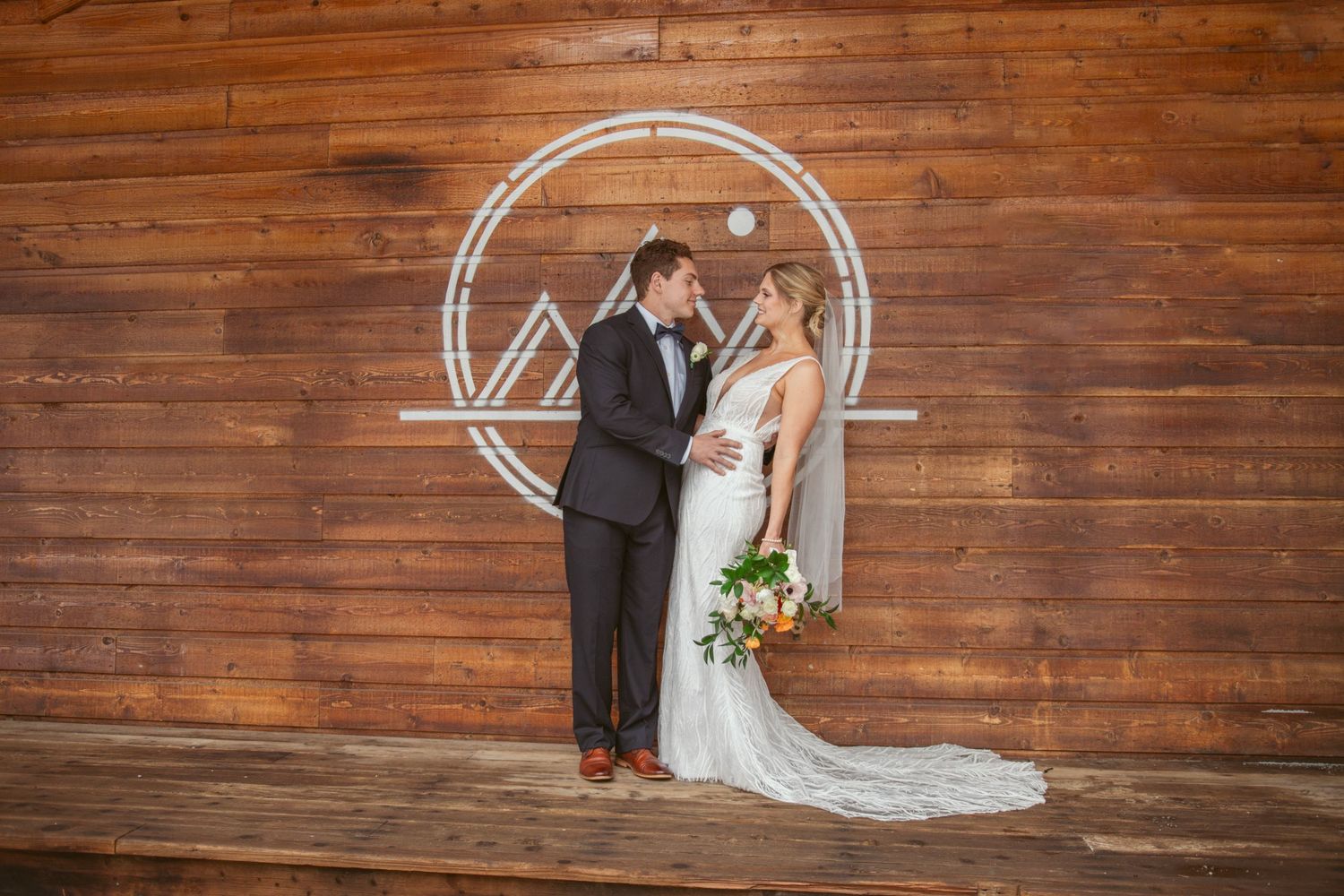 Wedding ceremony setup with wooden wall backdrop and circular arch decorations.