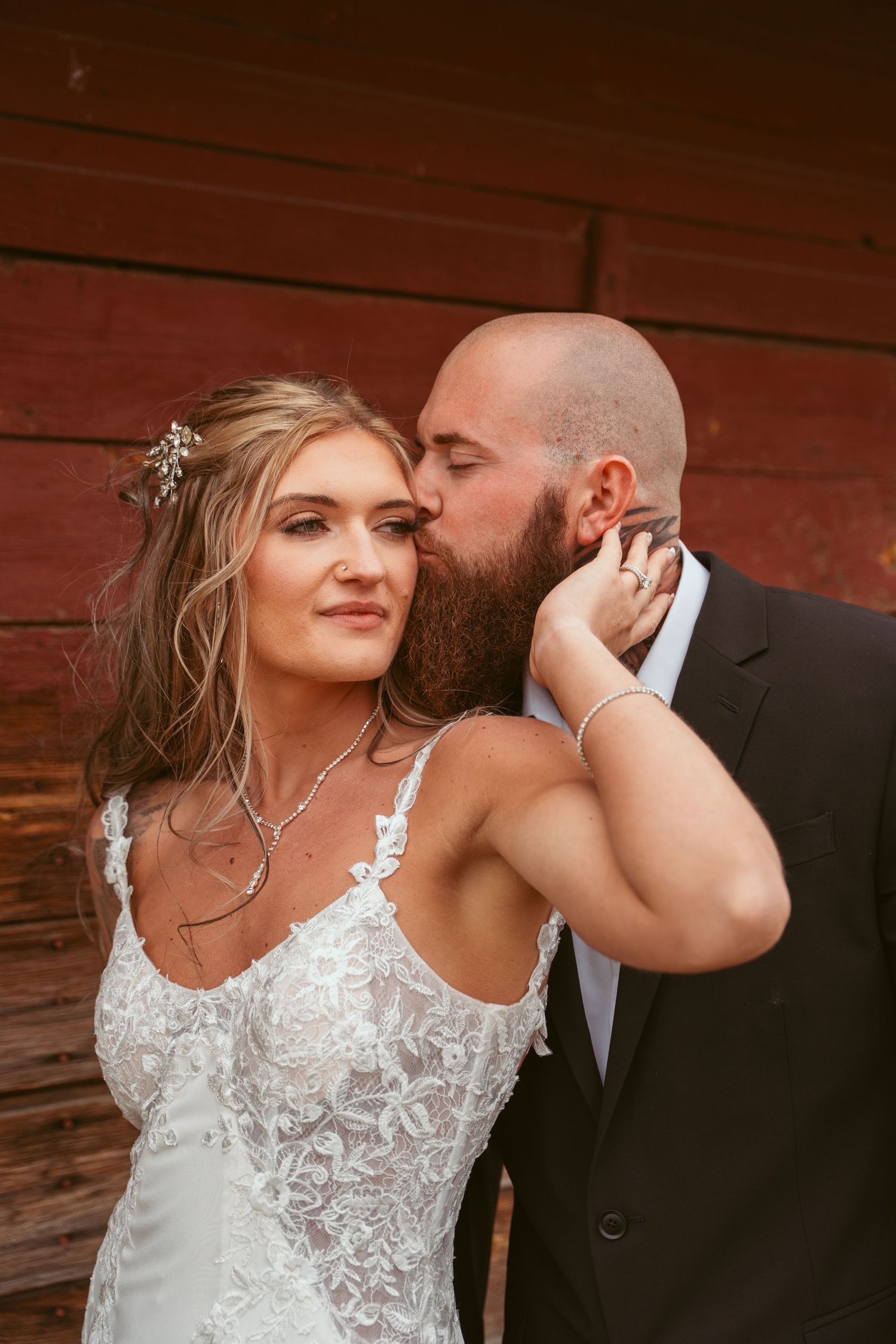 Romantic close-up wedding portrait against red barn backdrop.