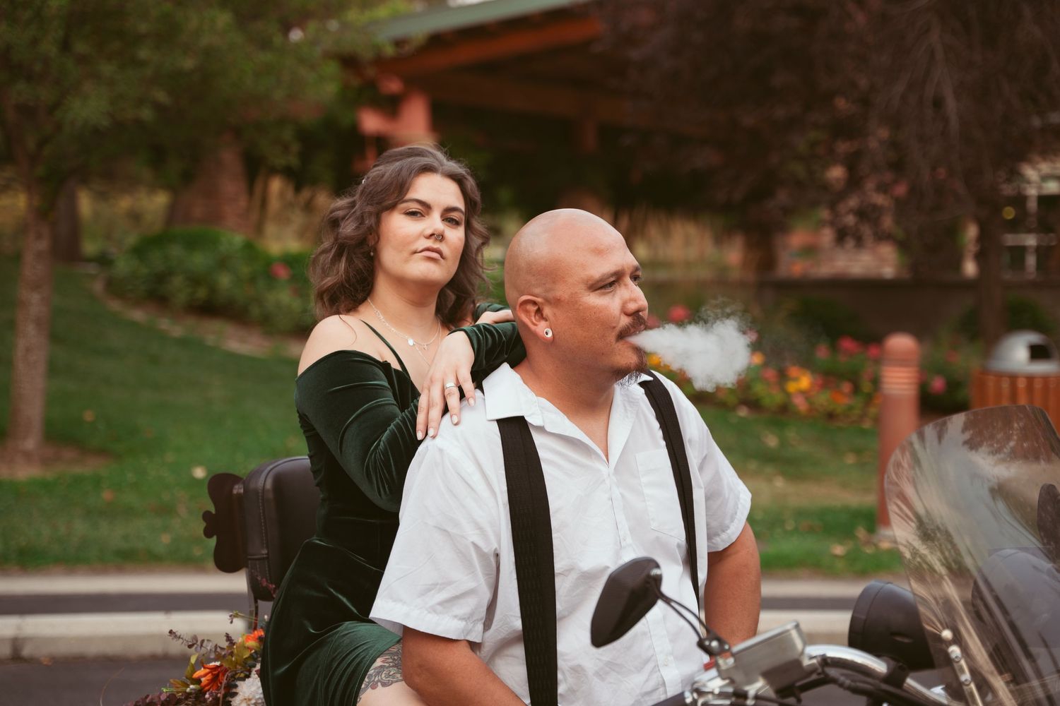 A couple shares tender moments while seated on a parked motorcycle.