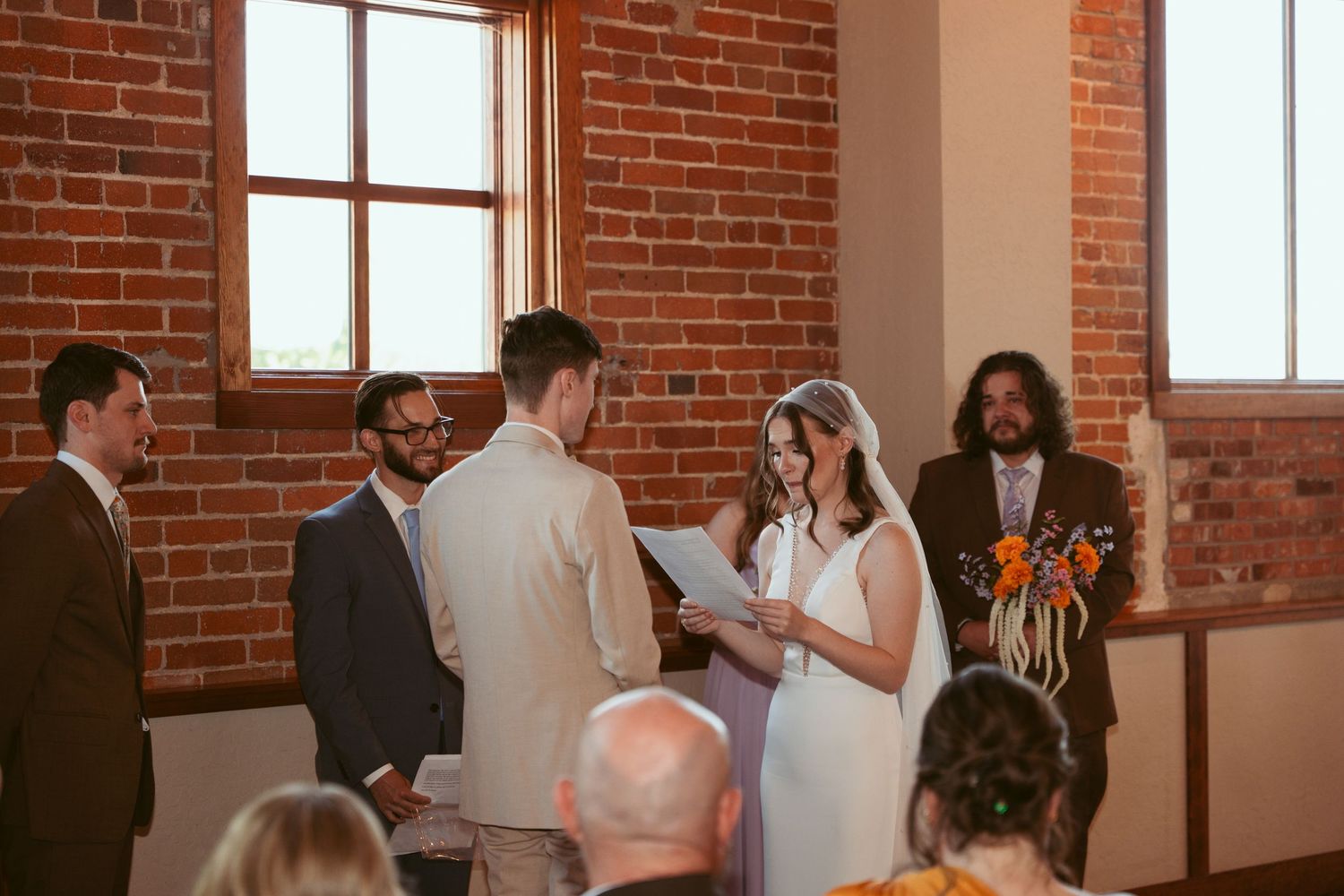 Sunlit wedding ceremony unfolding in industrial-style brick venue.