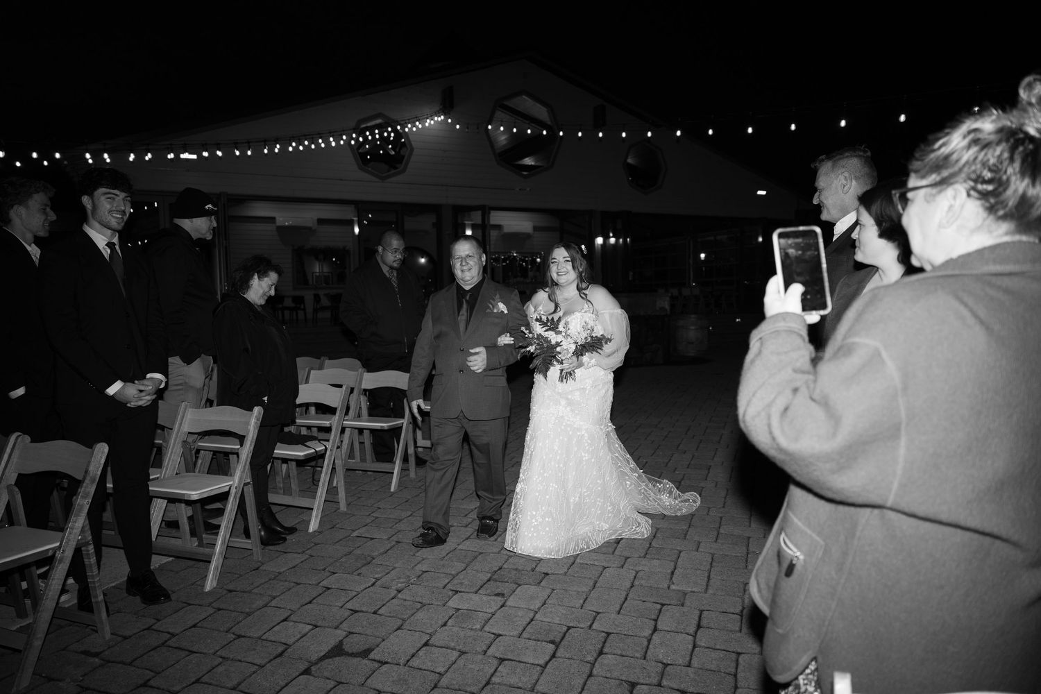 String lights illuminate an outdoor wedding reception venue at night.