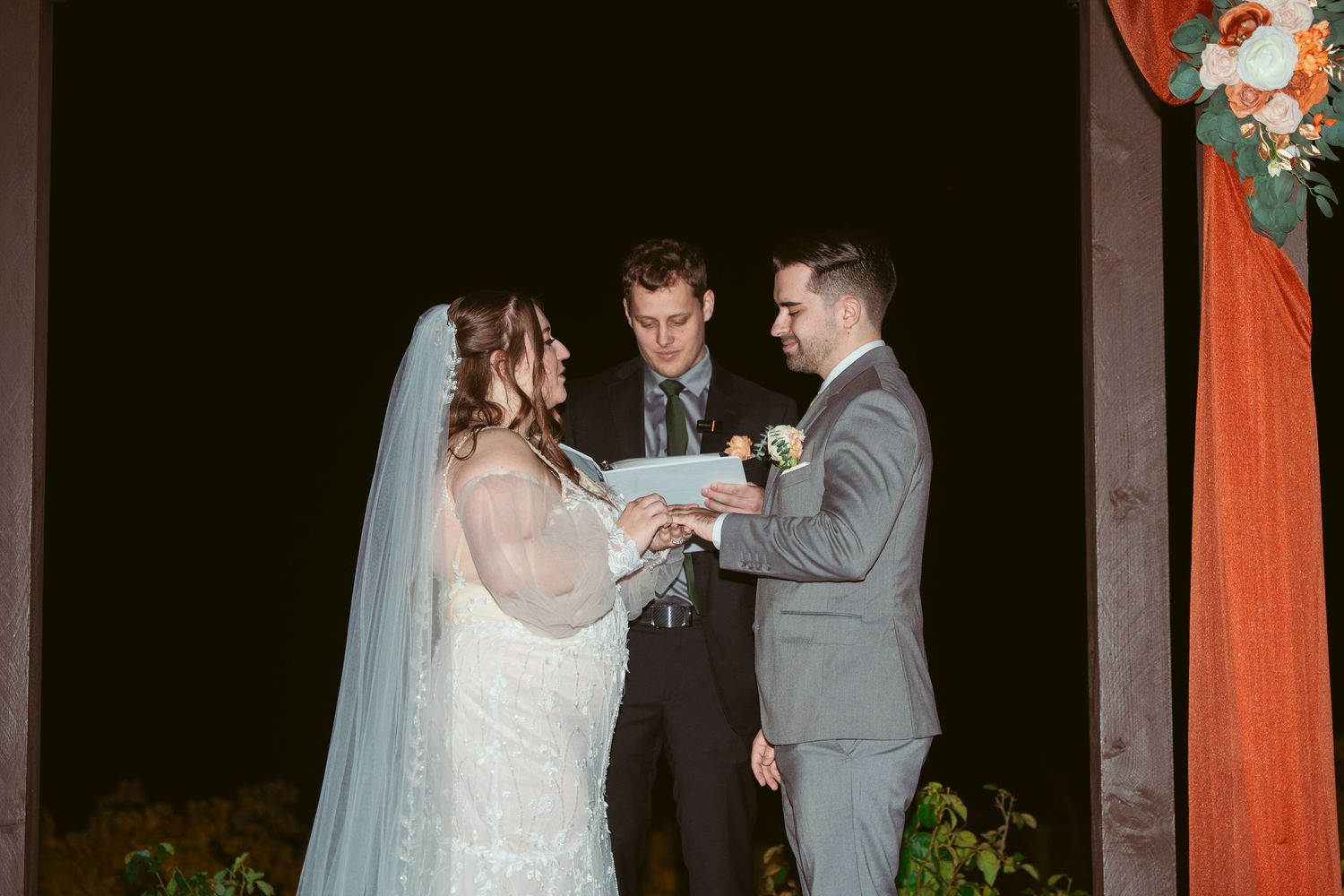 A wedding ceremony taking place with a couple exchanging vows under an officiant.