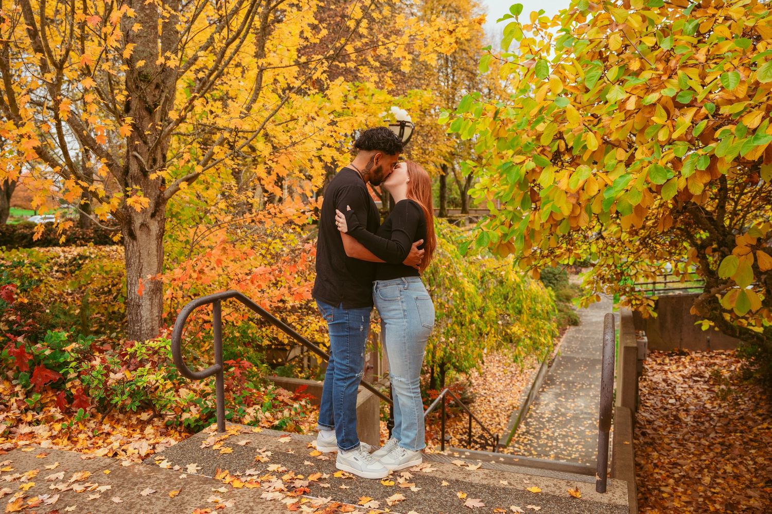 Autumn engagement photoshoot with couple among trees with golden leaves.