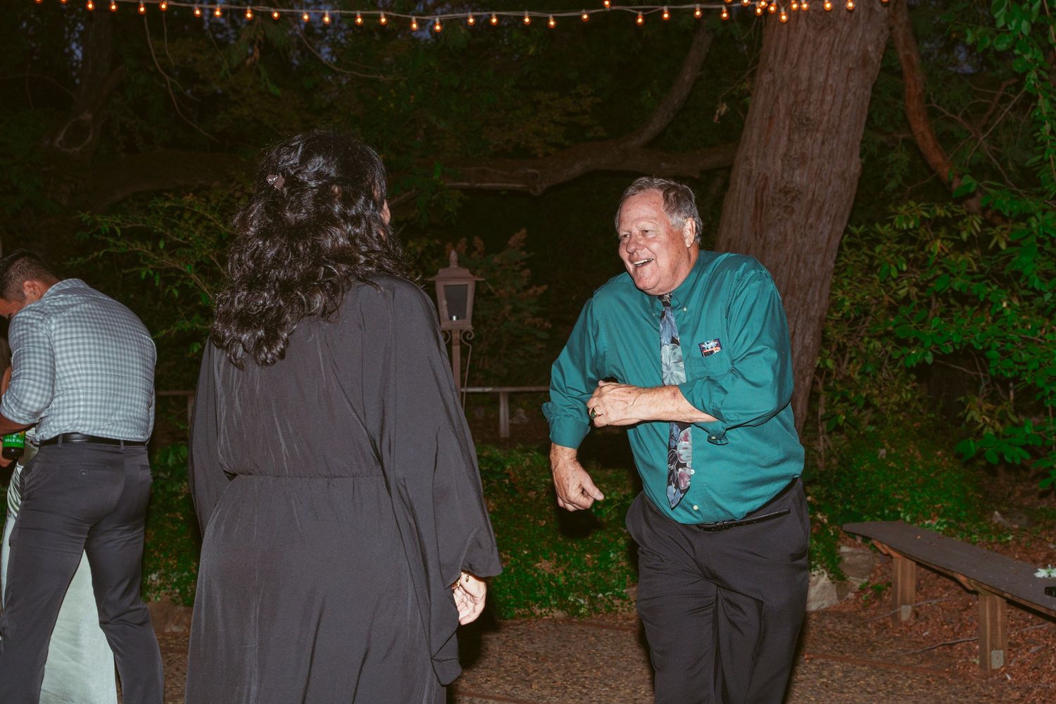 Wedding reception dance party at night with string lights creating a festive atmosphere.