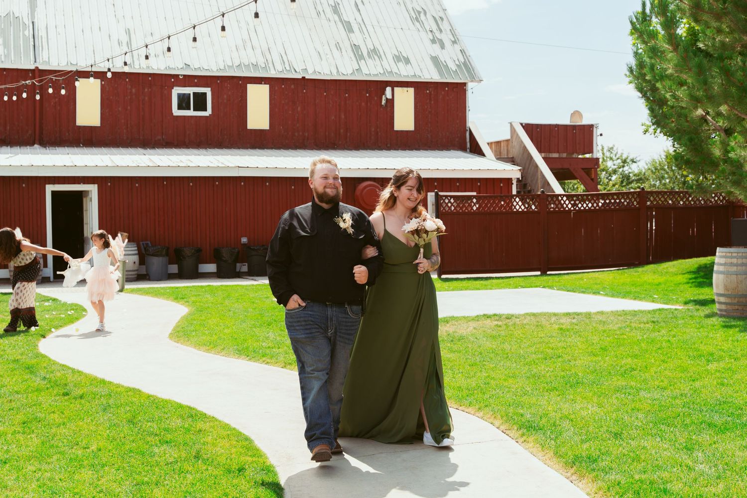 A red barn wedding venue with string lights and a grassy lawn in front.