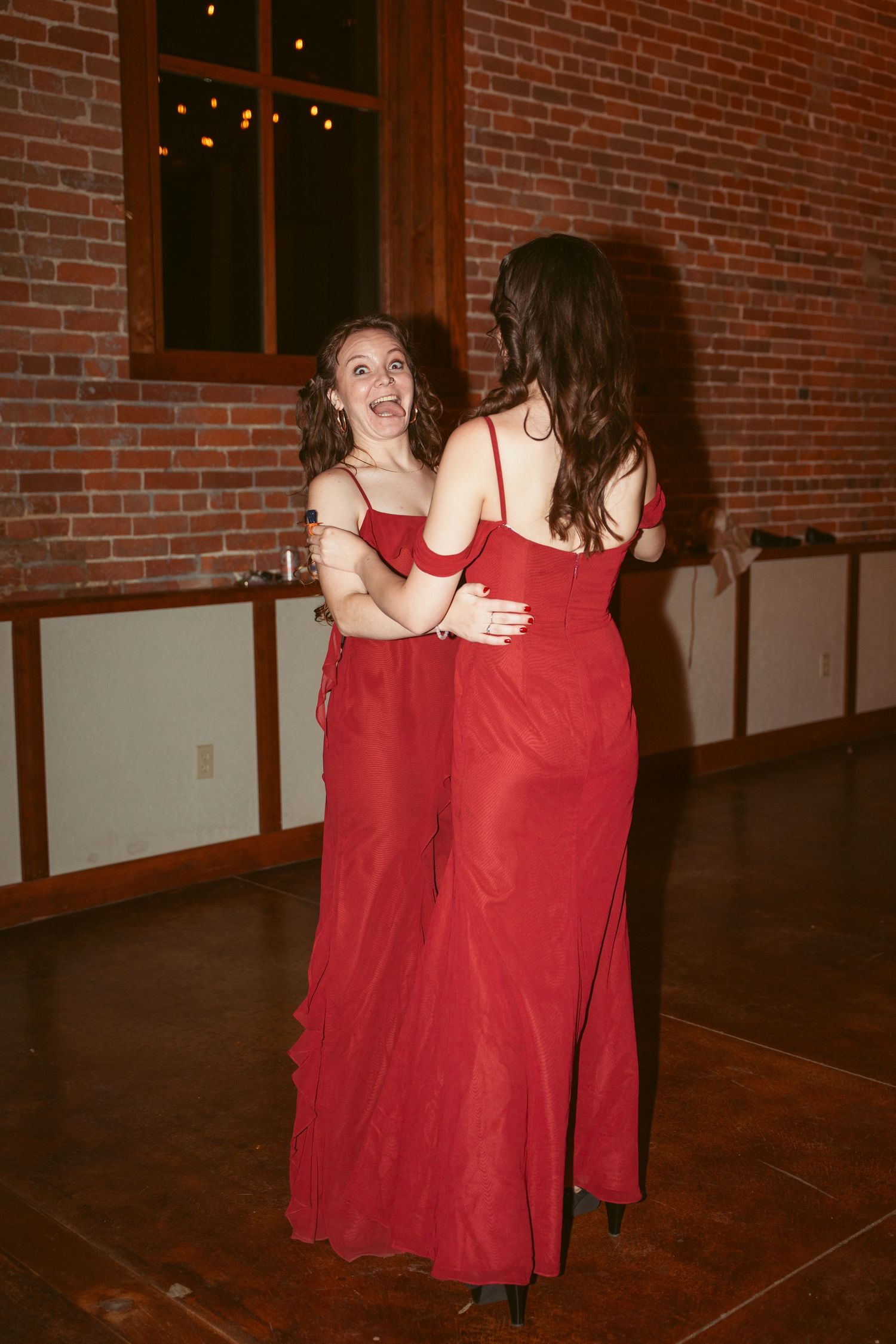 Bridesmaids in red dresses performing a dance routine at a wedding reception.