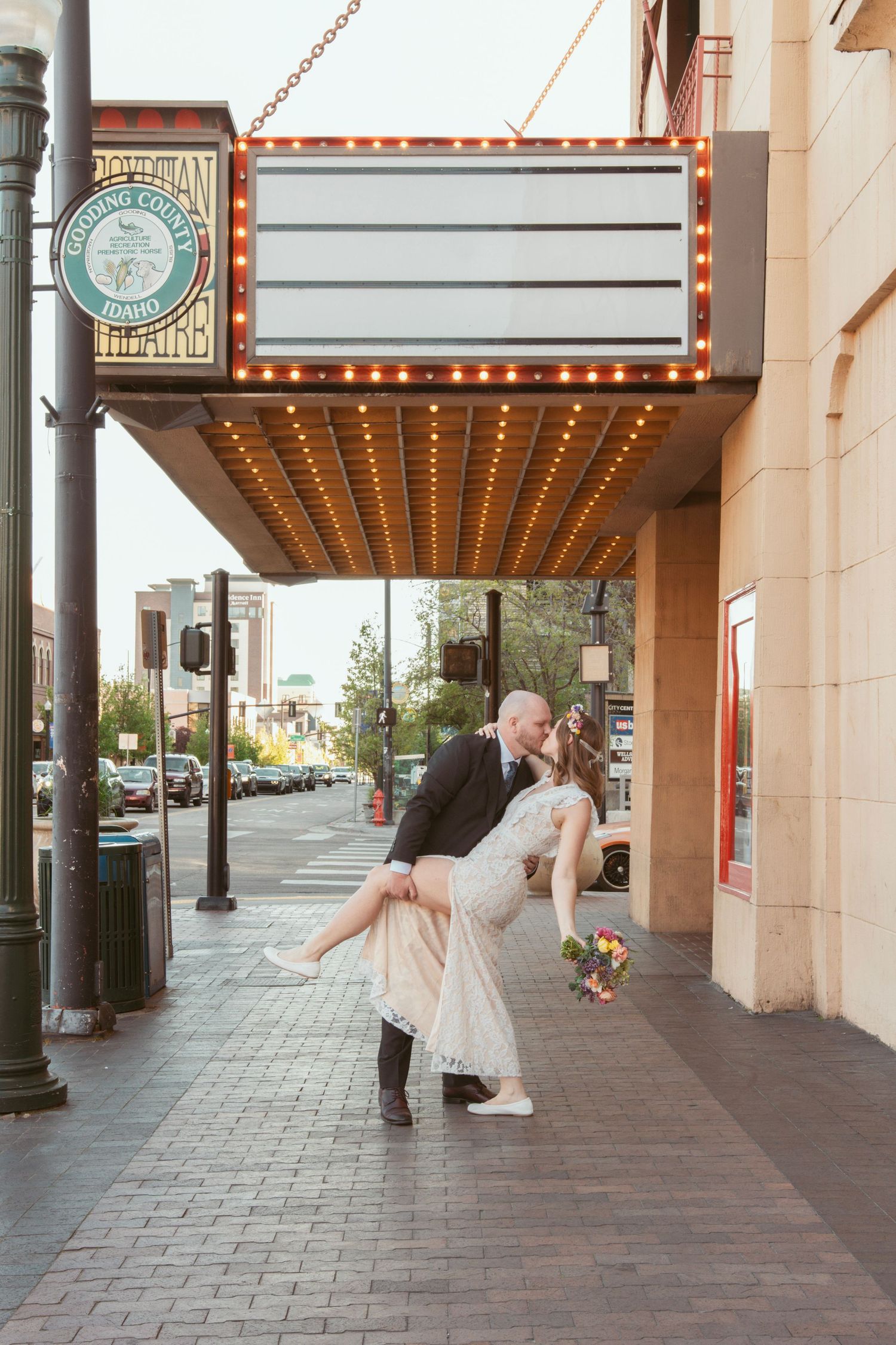 Couple performs series of romantic dance dips outside historic theater entrance.