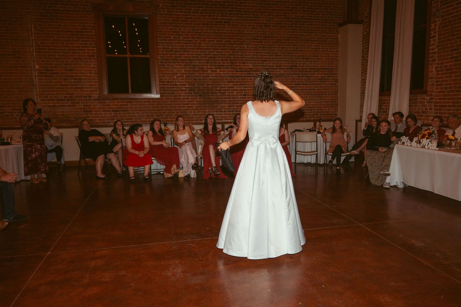 Wedding celebration with dancing in a spacious brick-walled venue.
