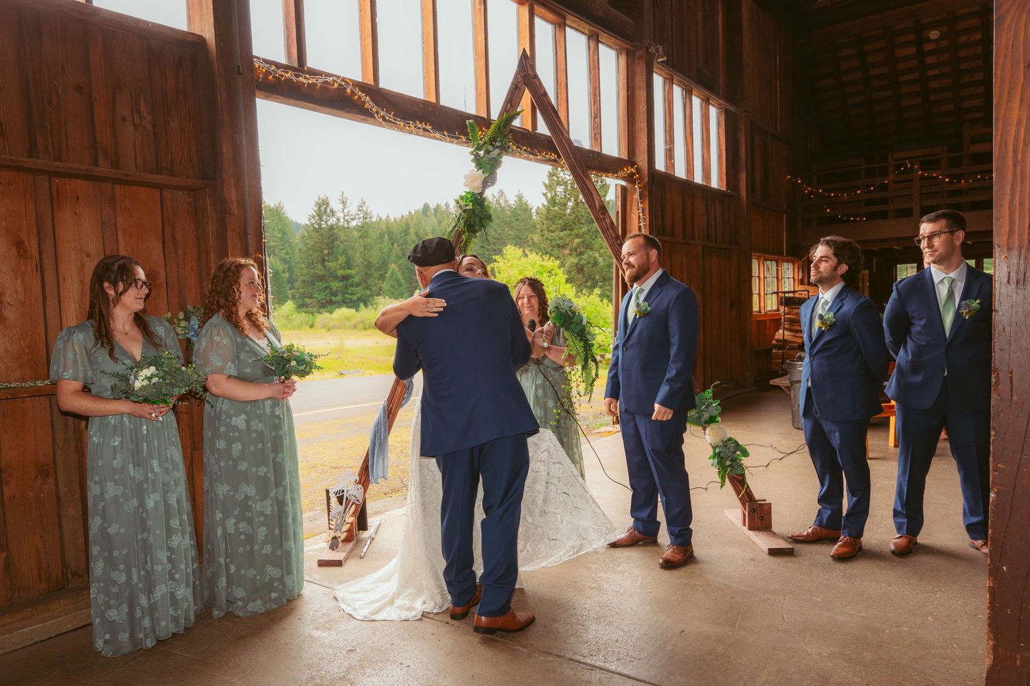 Wedding party watching emotional first look reveal inside rustic barn venue.