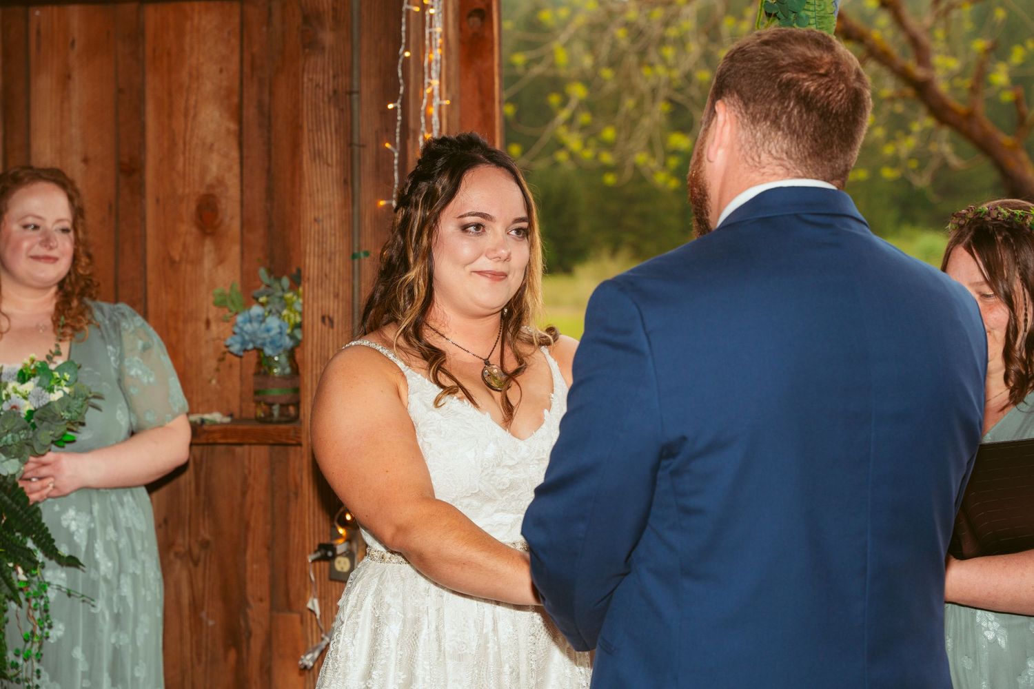 Wedding party celebrates inside rustic barn venue decorated with twinkle lights.
