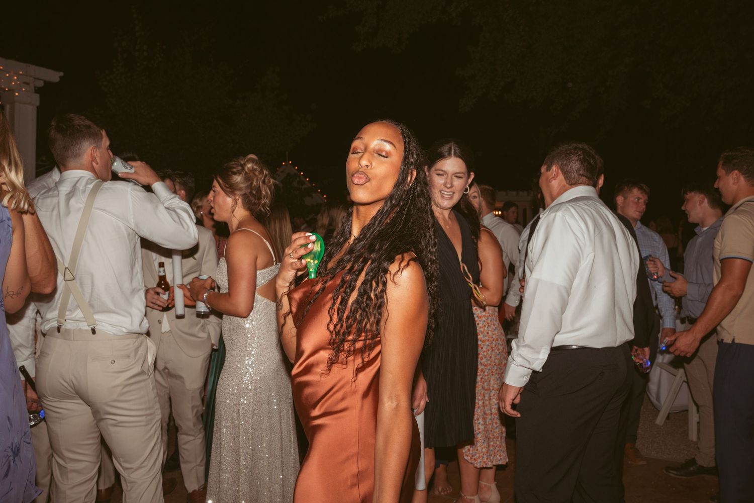 Guests enjoying themselves on a dimly lit outdoor dance floor at a wedding reception.