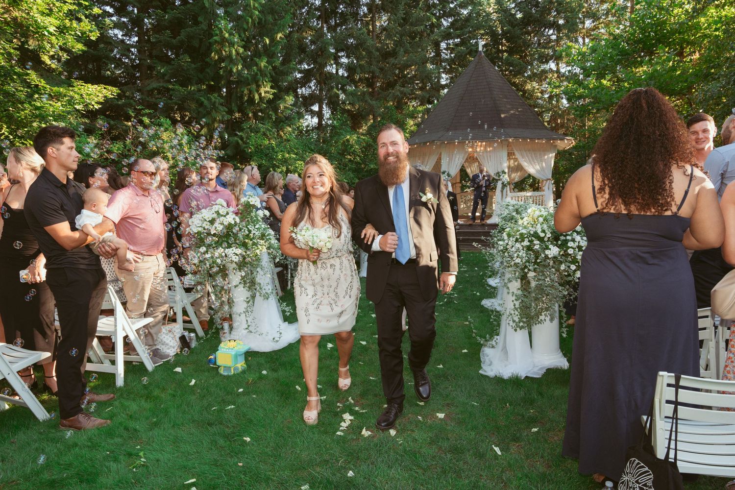 Outdoor wedding reception with guests dancing and socializing in a verdant garden setting.