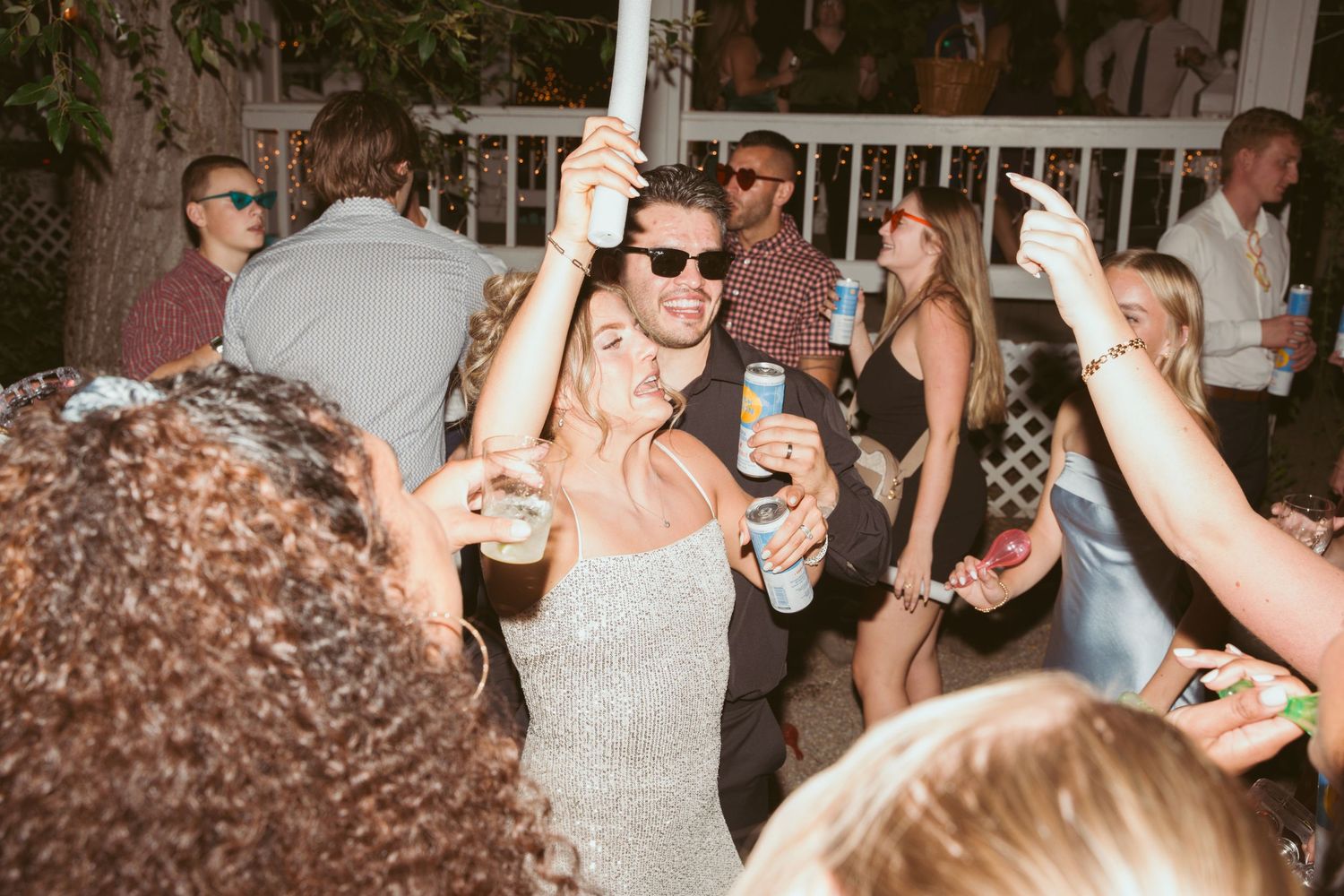 Guests celebrating and raising drinks during a festive outdoor wedding reception.