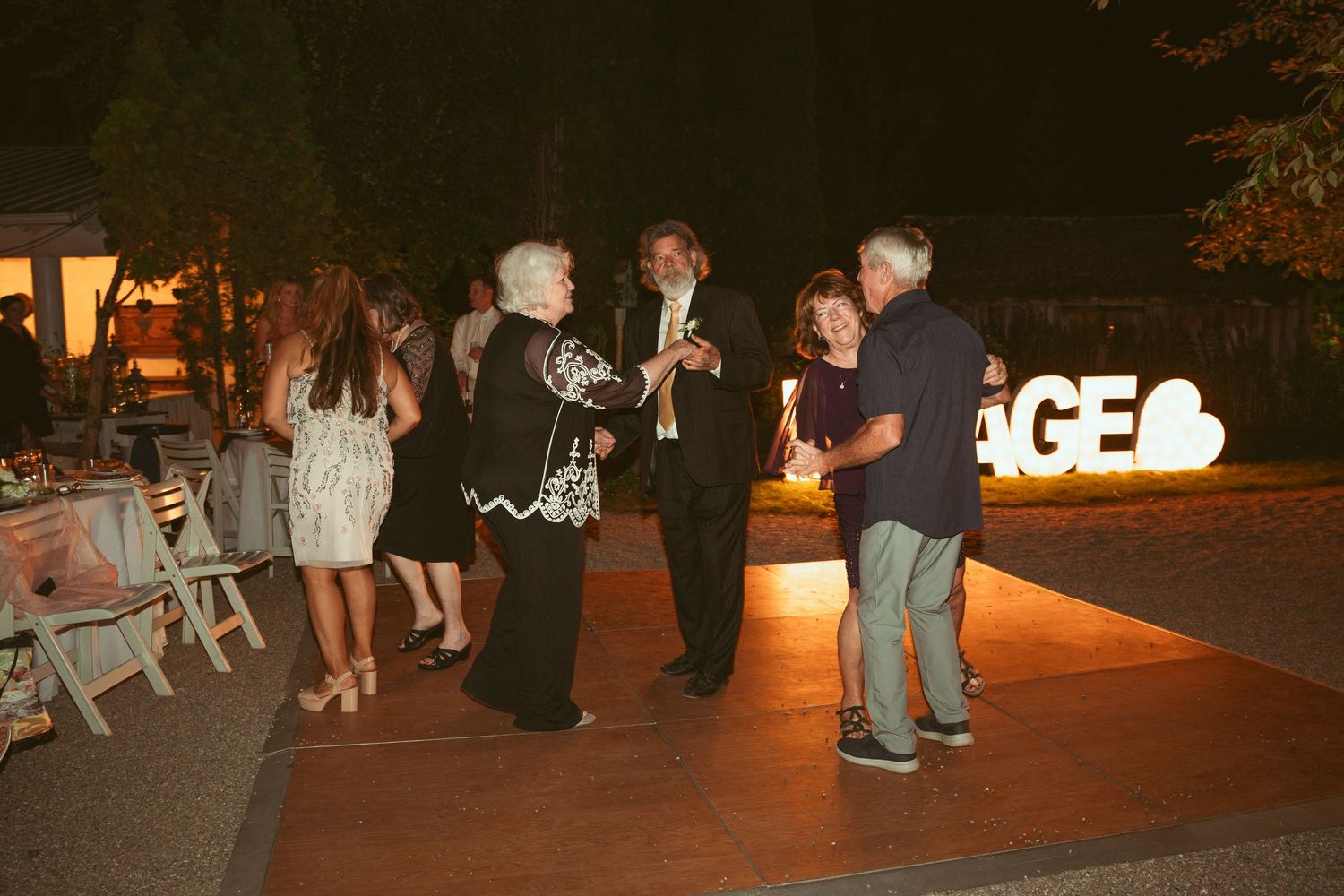 Wedding reception dance floor with string lights illuminating the outdoor space at night.