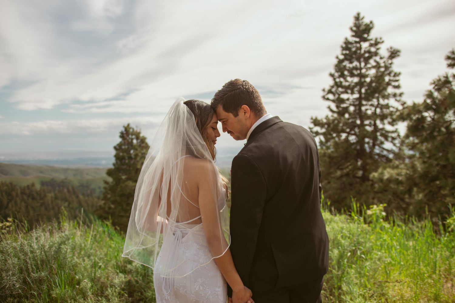 An intimate wedding moment captured against a backdrop of mountains and evergreen trees.
