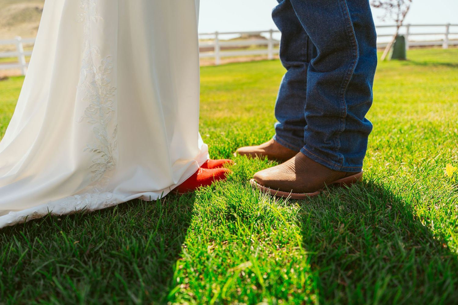Close-up shot of red shoes and boots on grass during a wedding photoshoot.