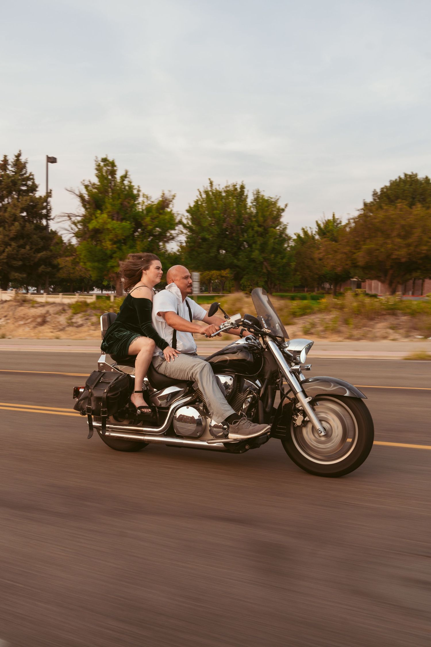 A motorcycle speeds down a street with trees in the background.