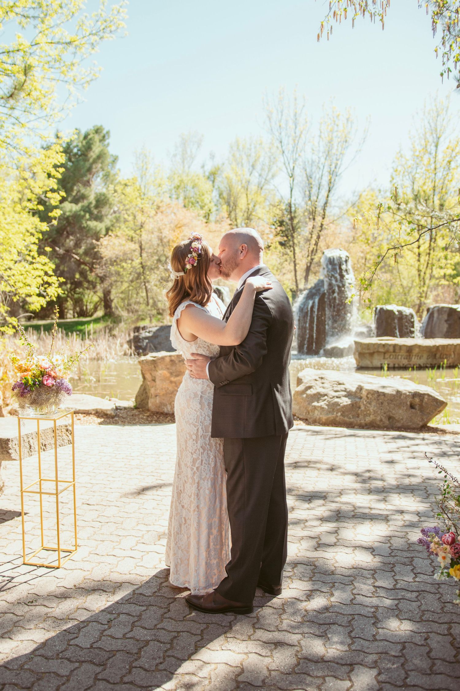 Spring wedding ceremony on stone patio with yellow blooming trees in background.