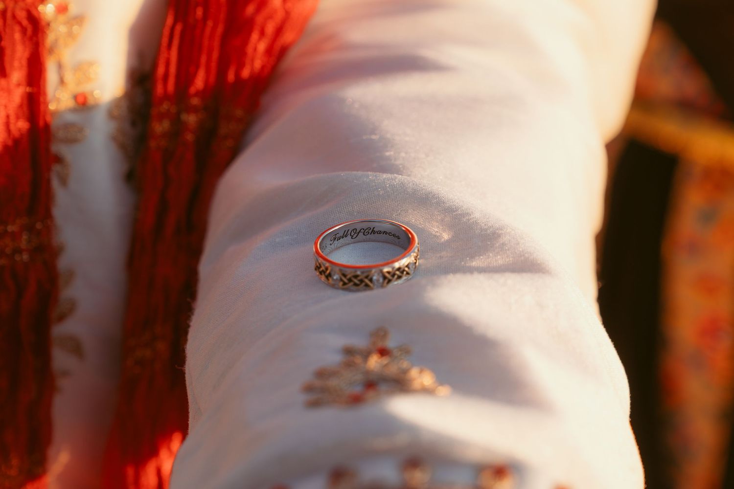 Close-up of wedding rings resting on white fabric with warm sunset lighting.