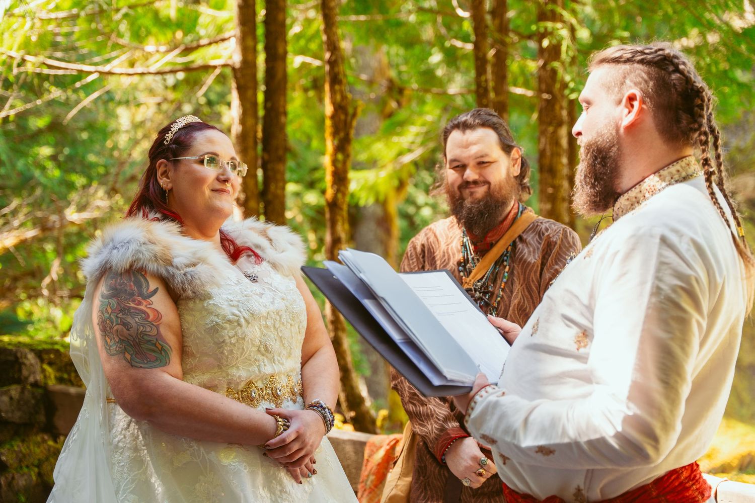 A wedding ceremony moment in a sun-dappled forest with medieval-themed attire.
