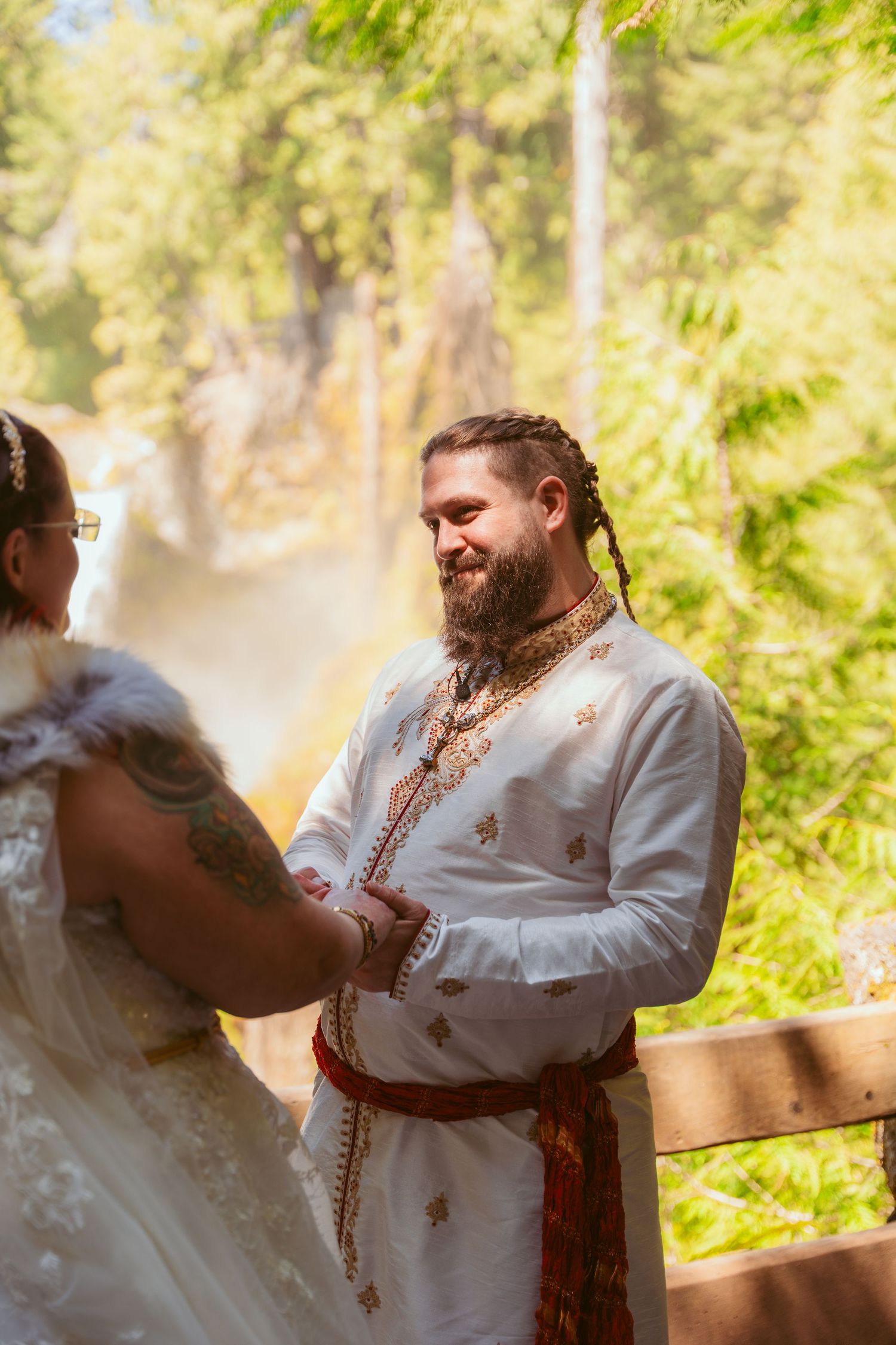 A couple performs their first dance in medieval-inspired wedding attire surrounded by forest greenery.