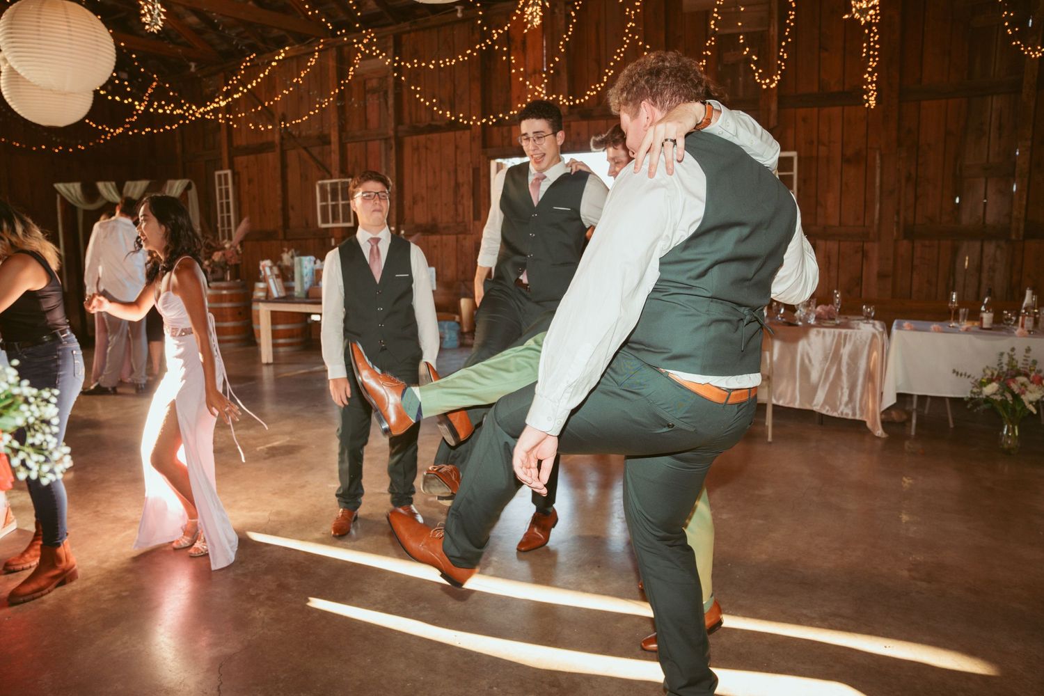 Wedding celebration in a barn with string lights and paper lanterns creating a warm atmosphere.