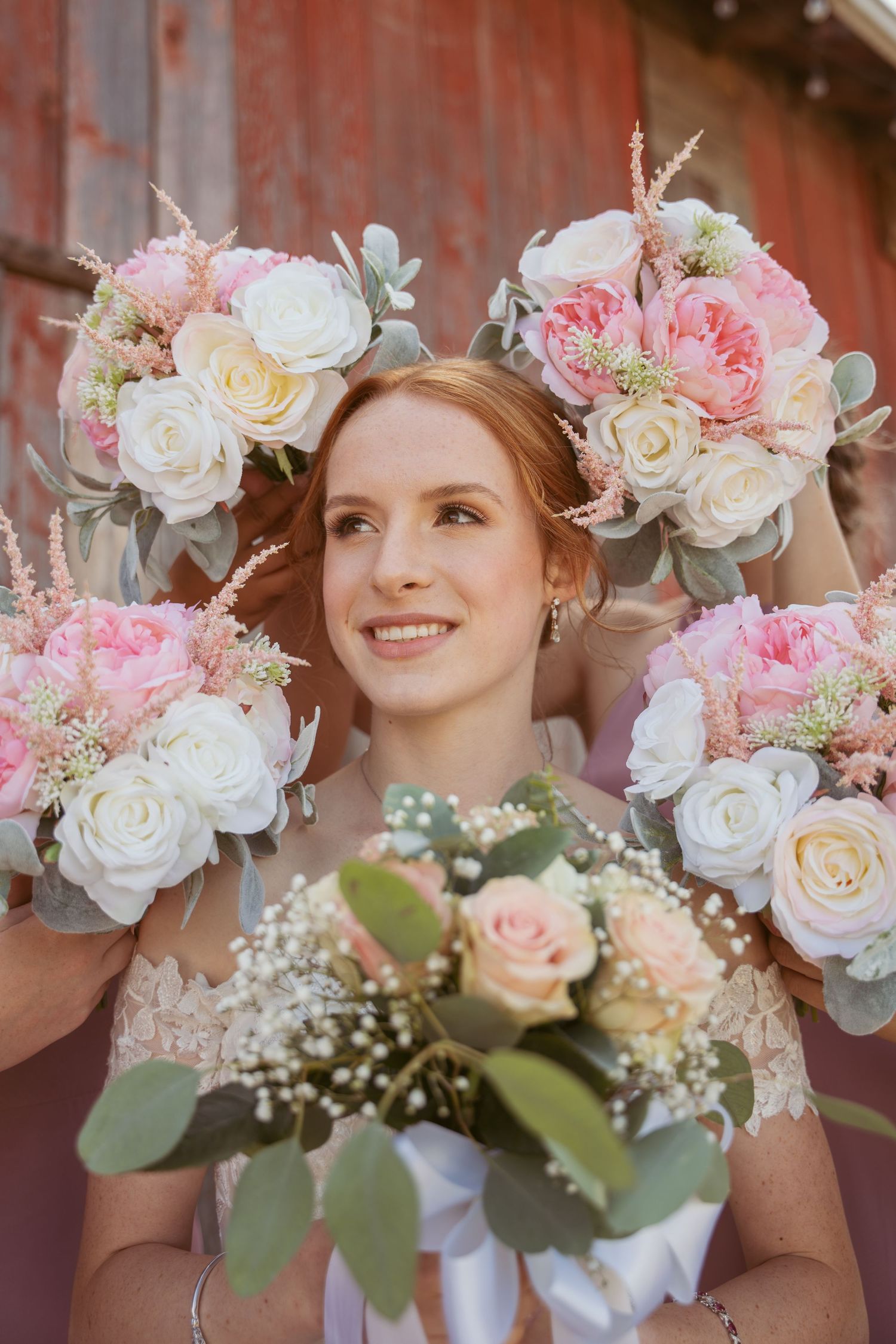 Elegant bridal bouquets with pink and white roses, baby's breath, and greenery tied with white ribbons.