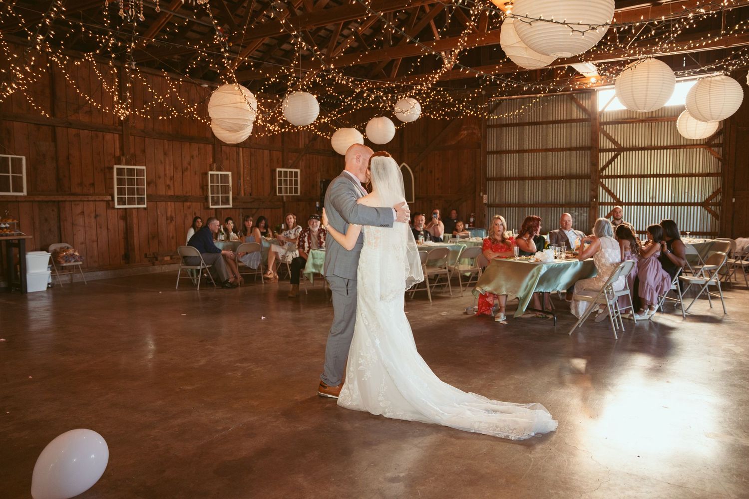 Elegant dance moves in a rustic barn venue with twinkling lights and festive decorations.