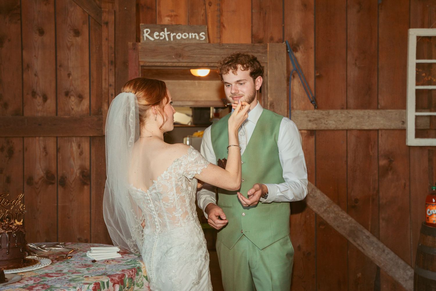 A couple shares a playful moment during their rustic barn wedding reception.