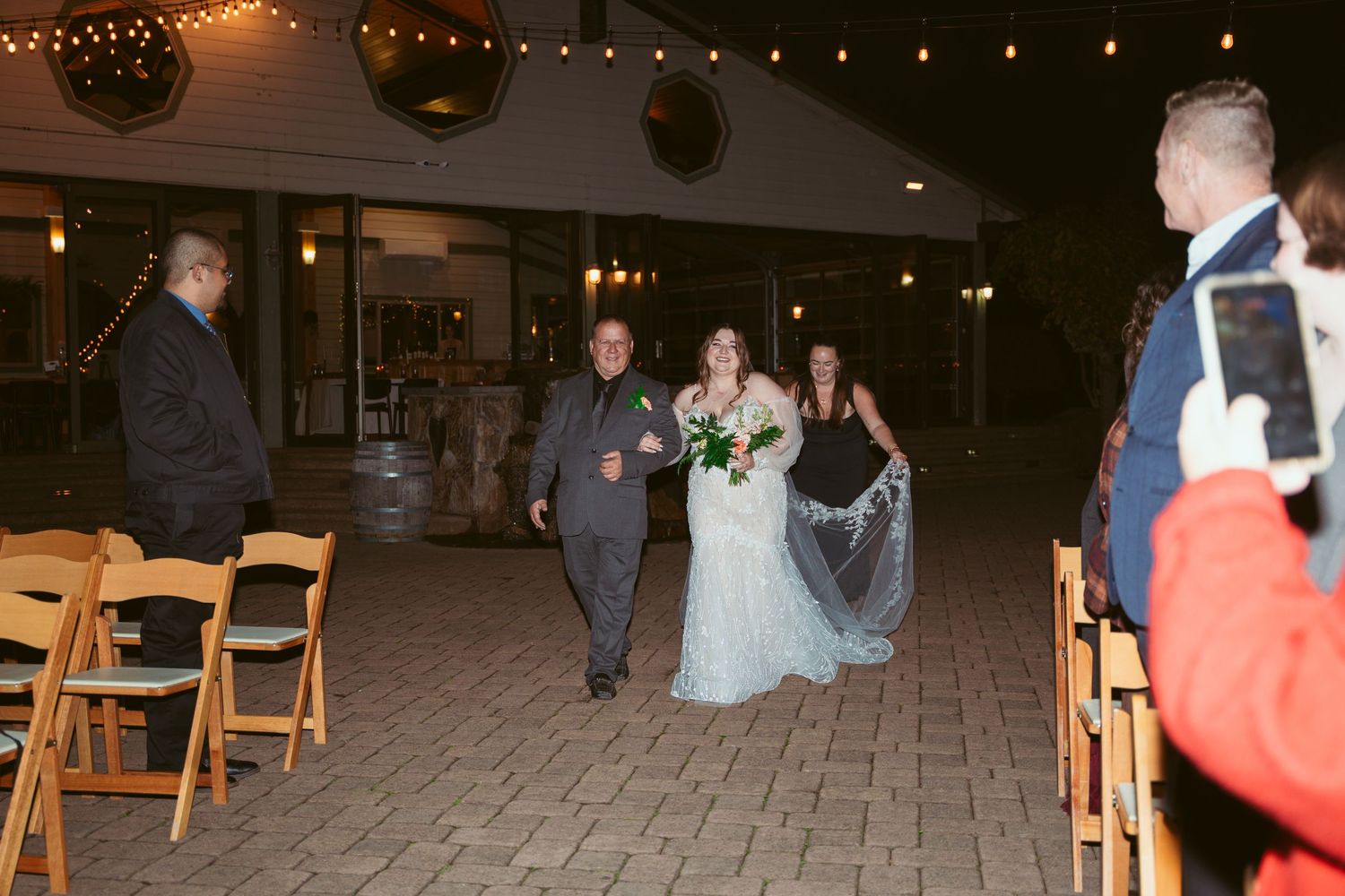 Wedding guests gather on an outdoor patio during an evening celebration.