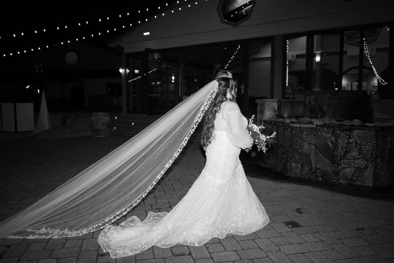 Black and white photo of wedding venue with dramatic lighting and flowing decor.