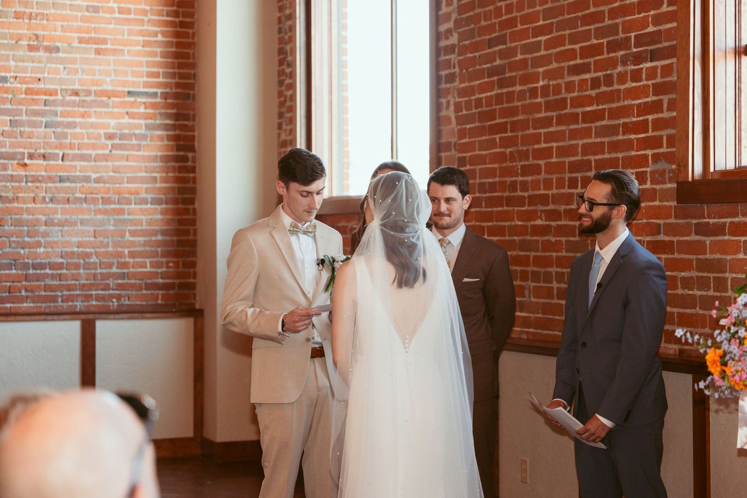 Wedding ceremony moments captured in warm-lit brick interior space.