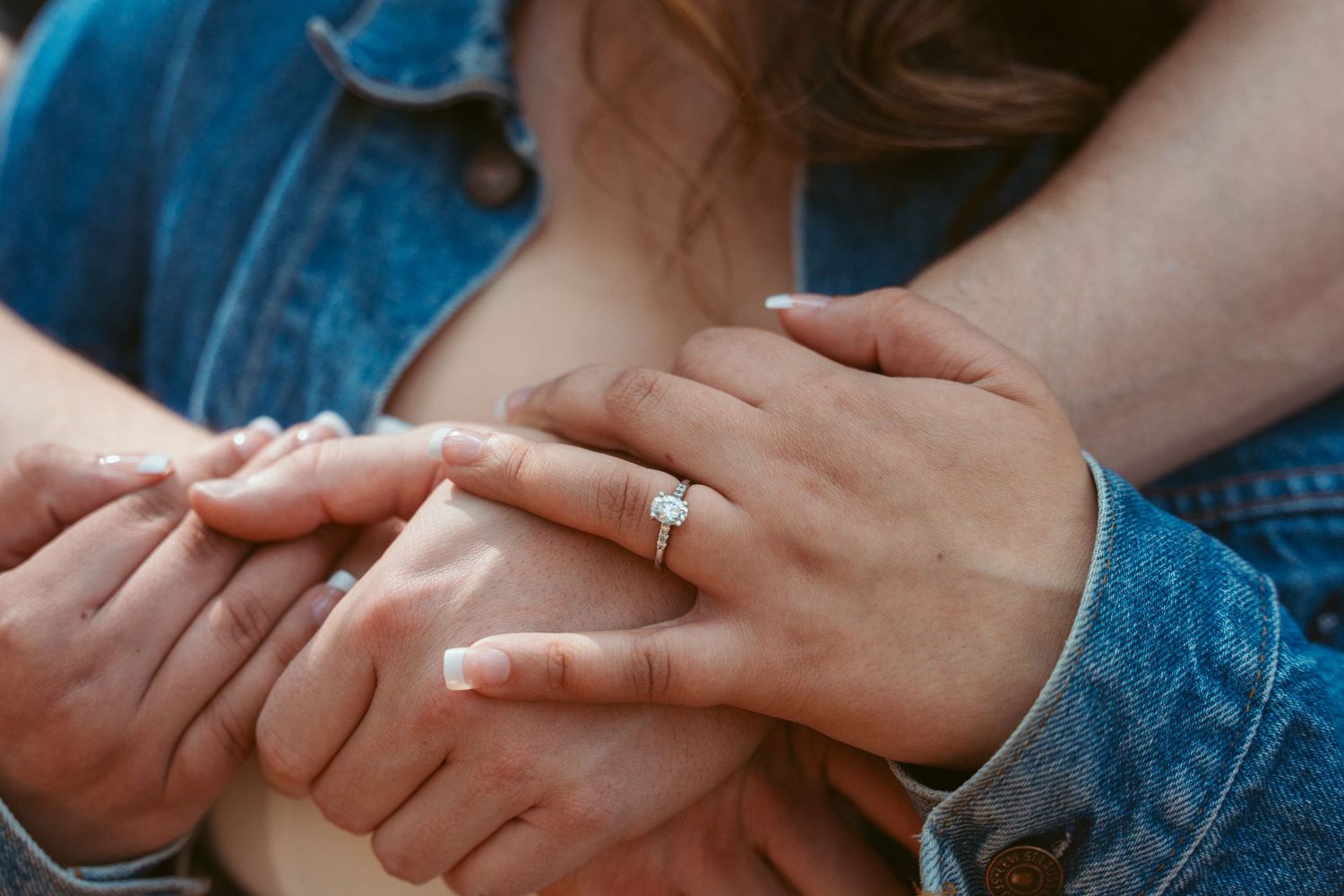 Close-up of hands tenderly touching in an intimate moment outdoors.