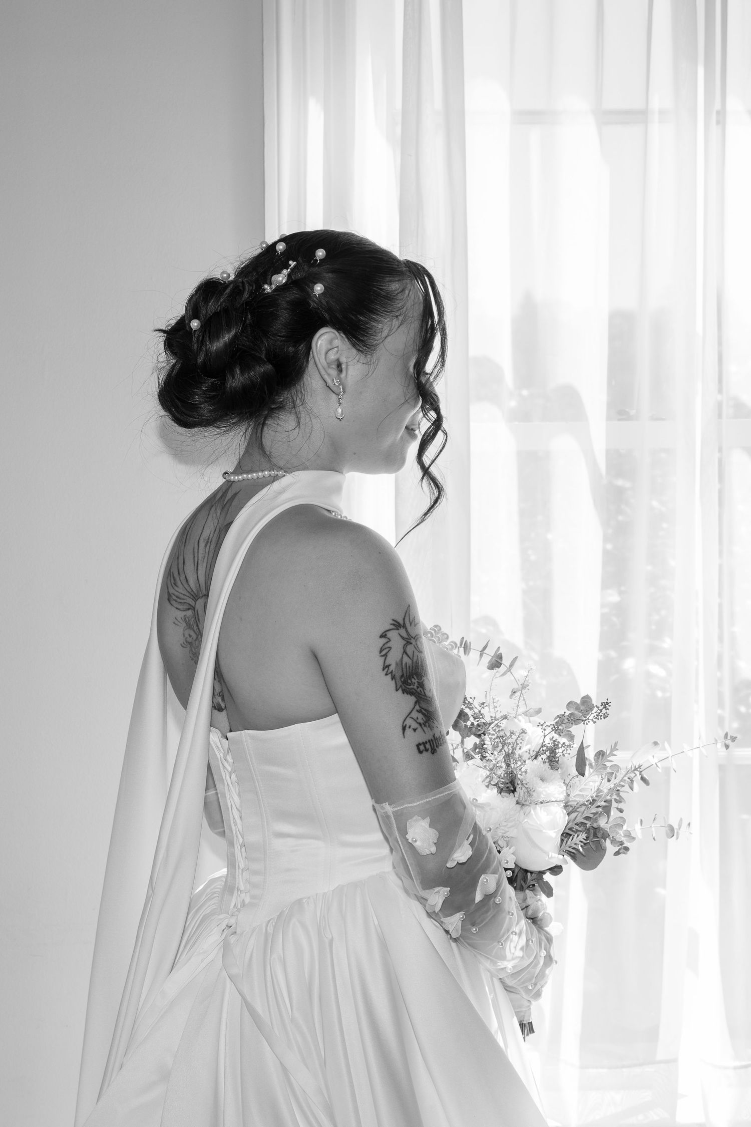 Artistic black and white portrait of bride in wedding dress by window light.
