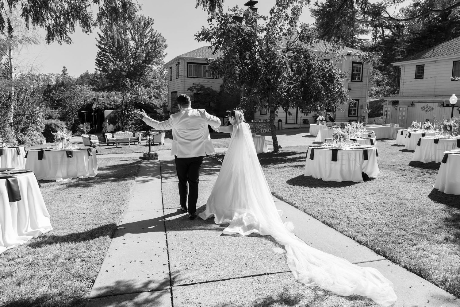 Black and white photo of an outdoor wedding ceremony with guests gathered on a sunny day.
