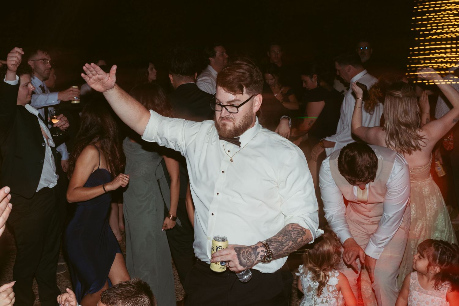 Crowd of people dancing together at a dimly lit indoor party venue.