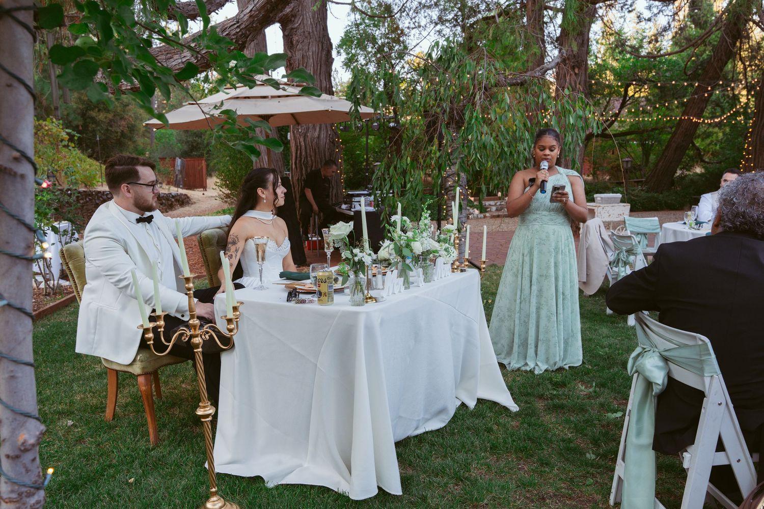 Outdoor wedding reception setup with white tablecloths and garden decor.