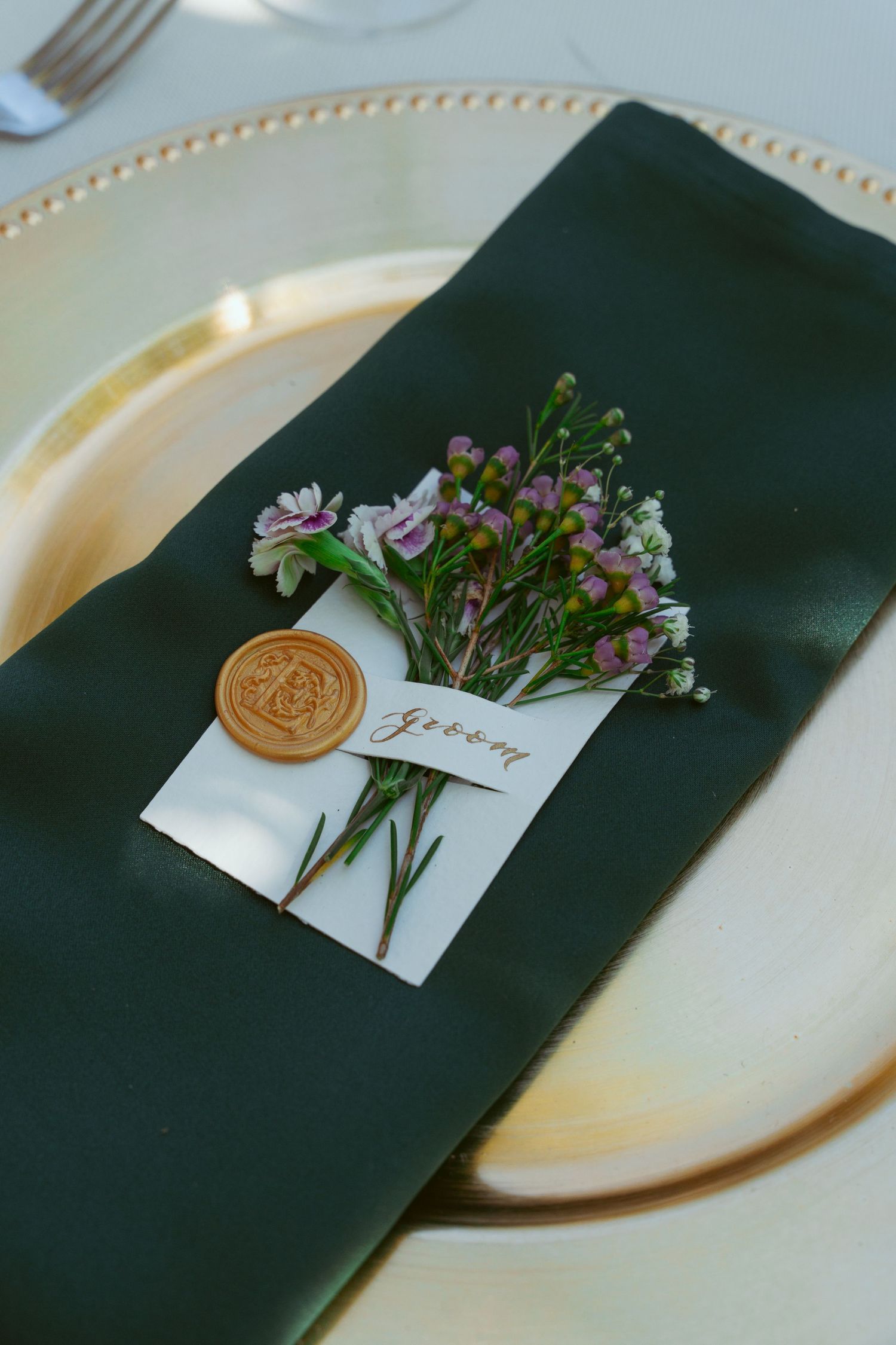 Place setting with dark napkin and delicate floral arrangement on cream colored plate.