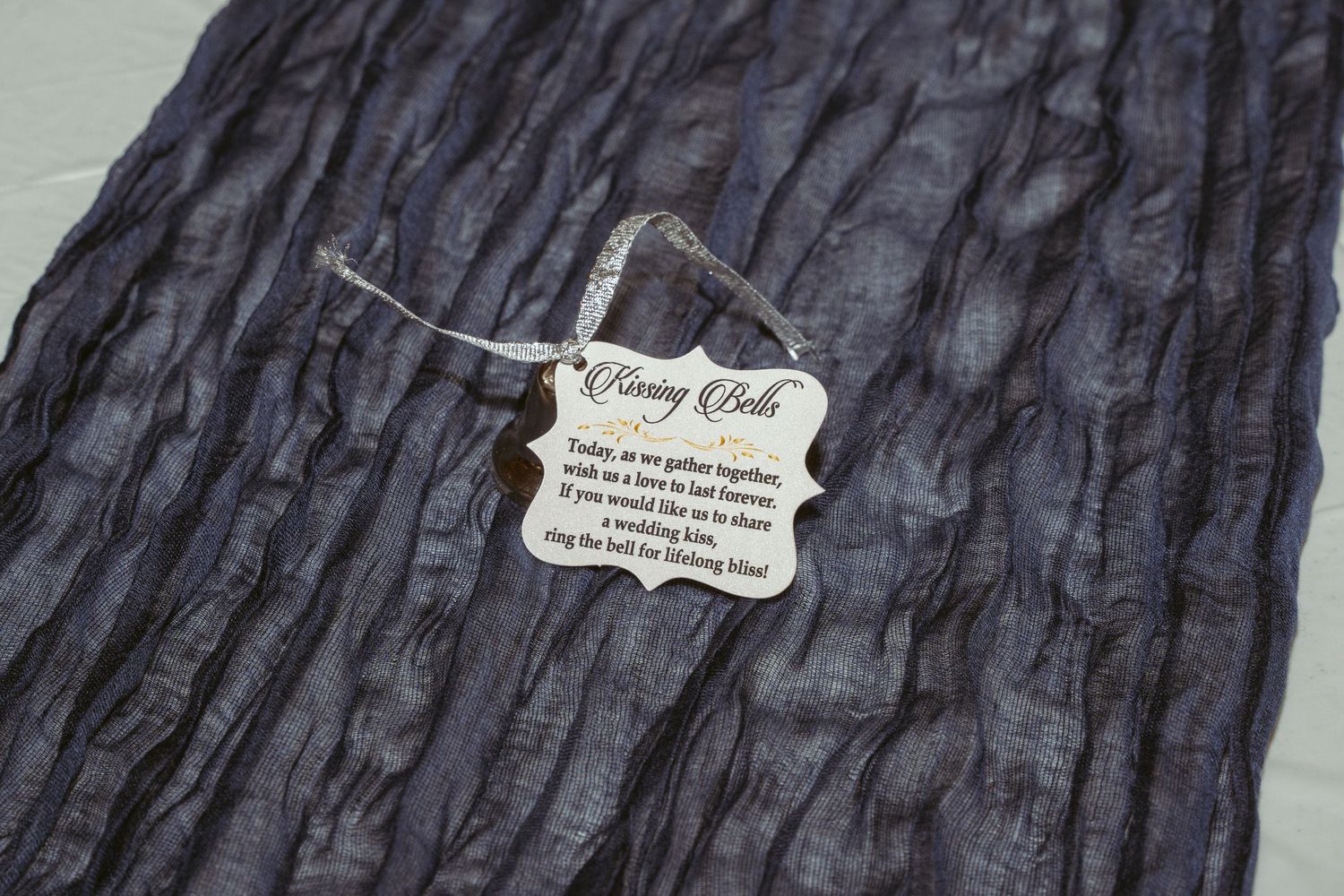 Close-up view of dark textured fabric with intricate pleating and ruching details creating a dimensional pattern.