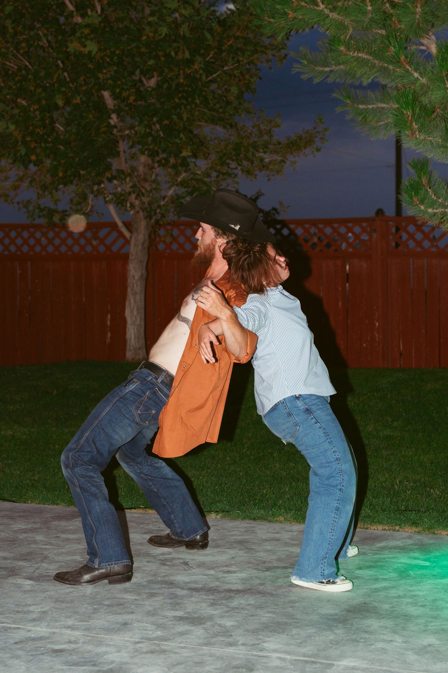 People dancing and playing games on a lit outdoor dance floor at night.